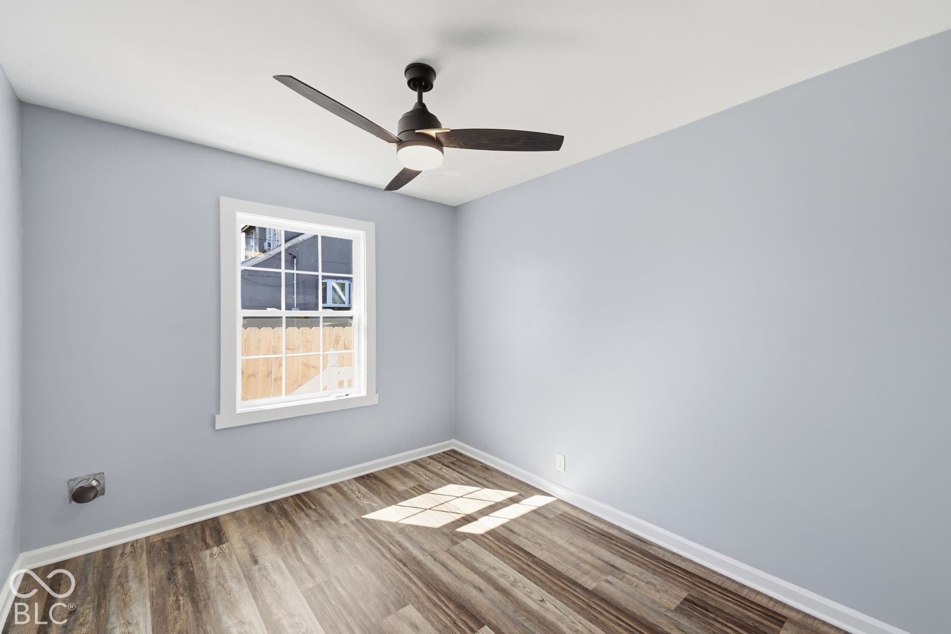 Wood-finish flooring, light blue wall paint, and a modern ceiling fan with integrated lighting