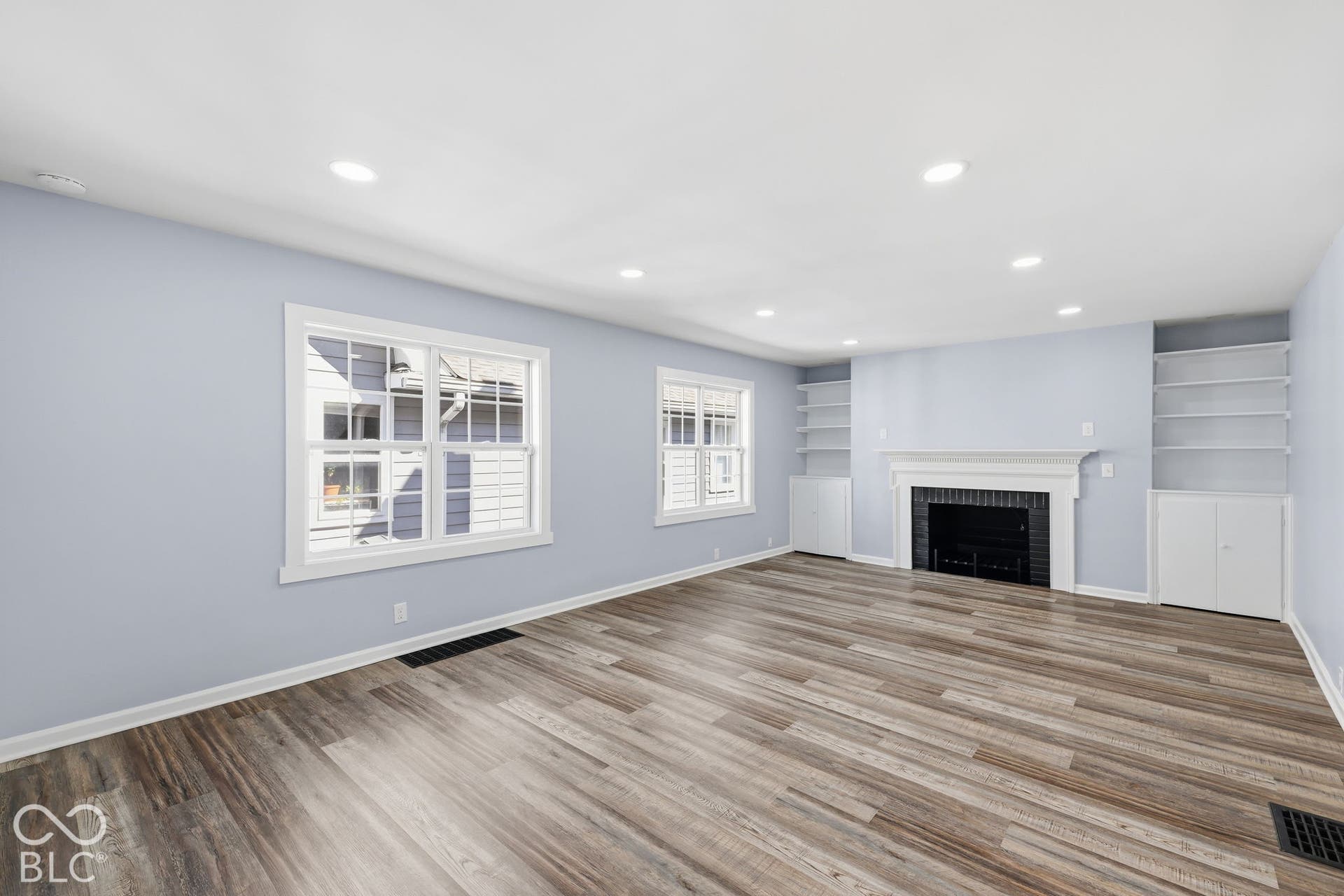 Recessed lighting illuminates the room, featuring wood-finish flooring and light-toned walls