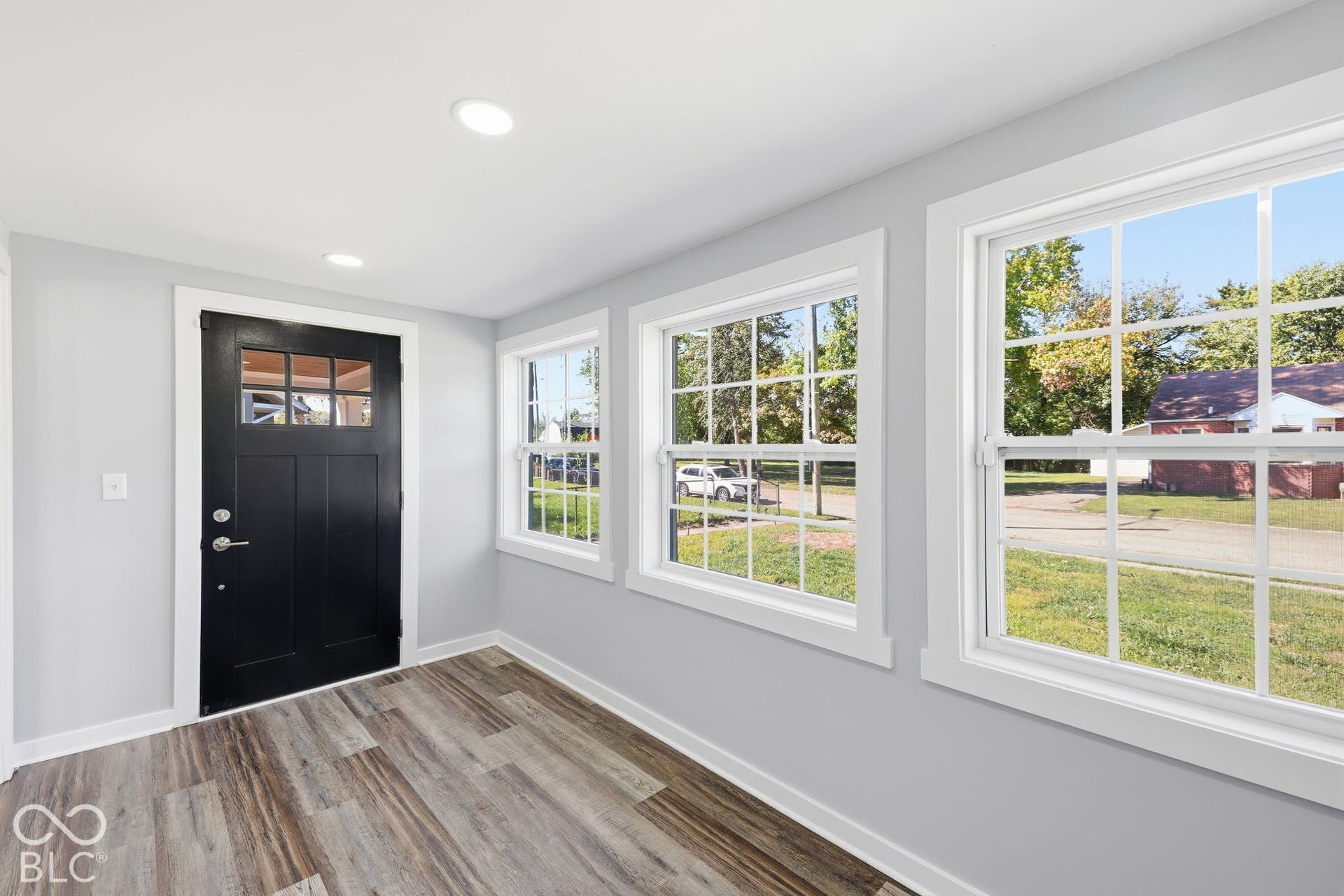 Entryway featuring a black paneled door with glass inserts, wood-finish flooring, light gray walls, and recessed lighting