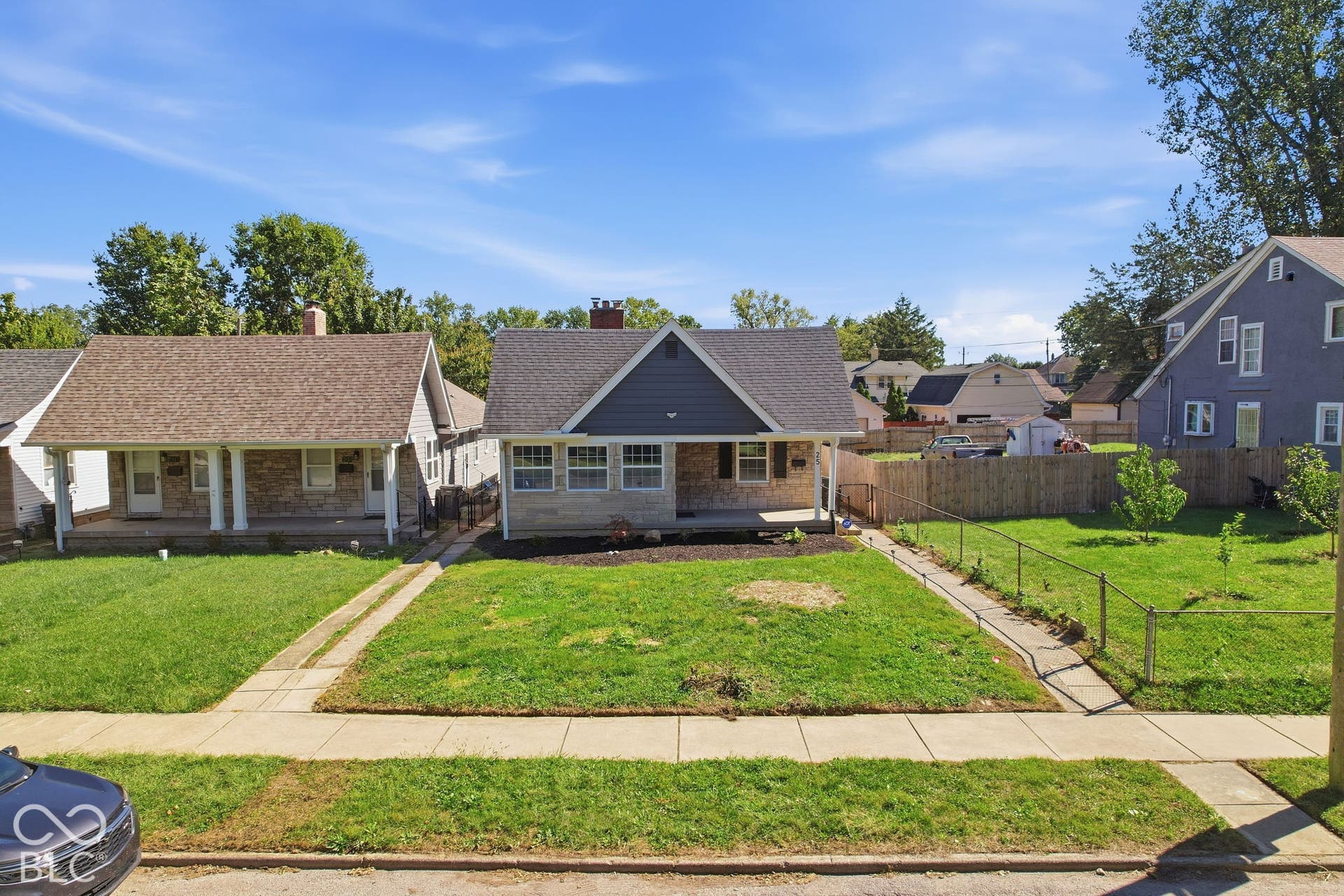 Gable-front home featuring a covered front porch, stone and siding exterior, and a manicured lawn