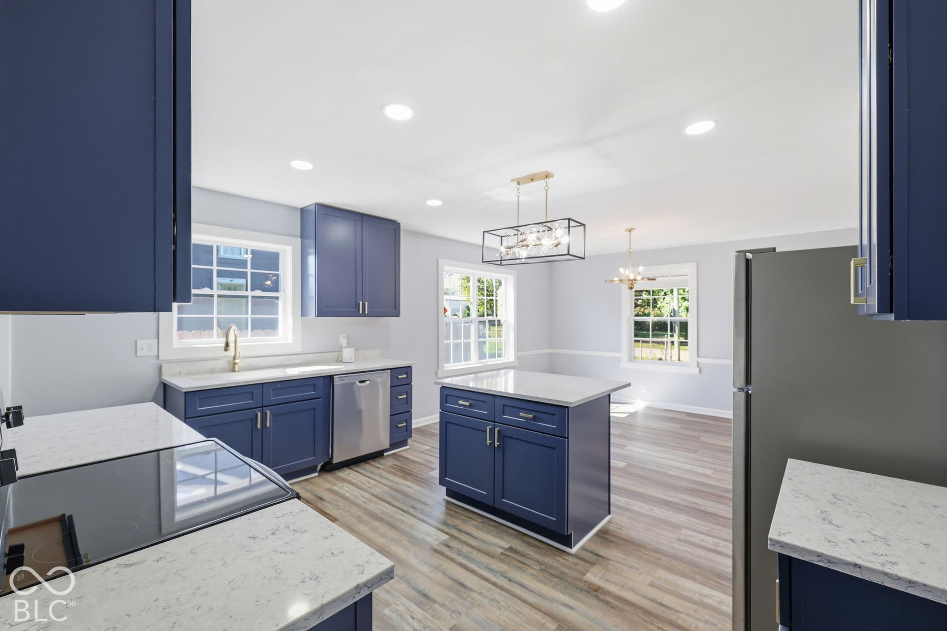 Kitchen featuring blue cabinetry, light-toned countertops, wood-finish flooring, recessed lighting, and stainless steel appliances