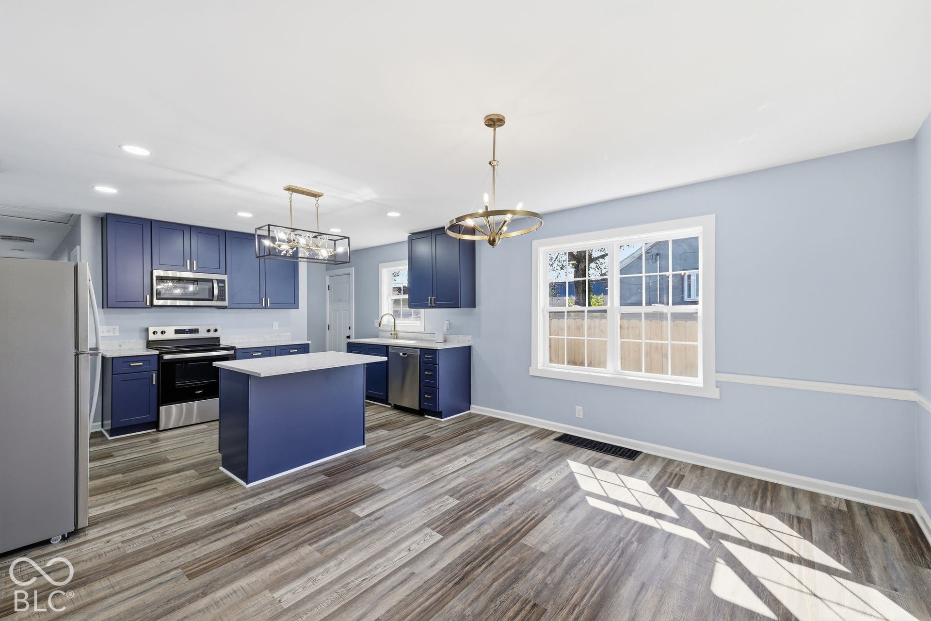 Kitchen featuring wood-finish flooring, blue cabinetry, stainless steel appliances, and a central island with a countertop