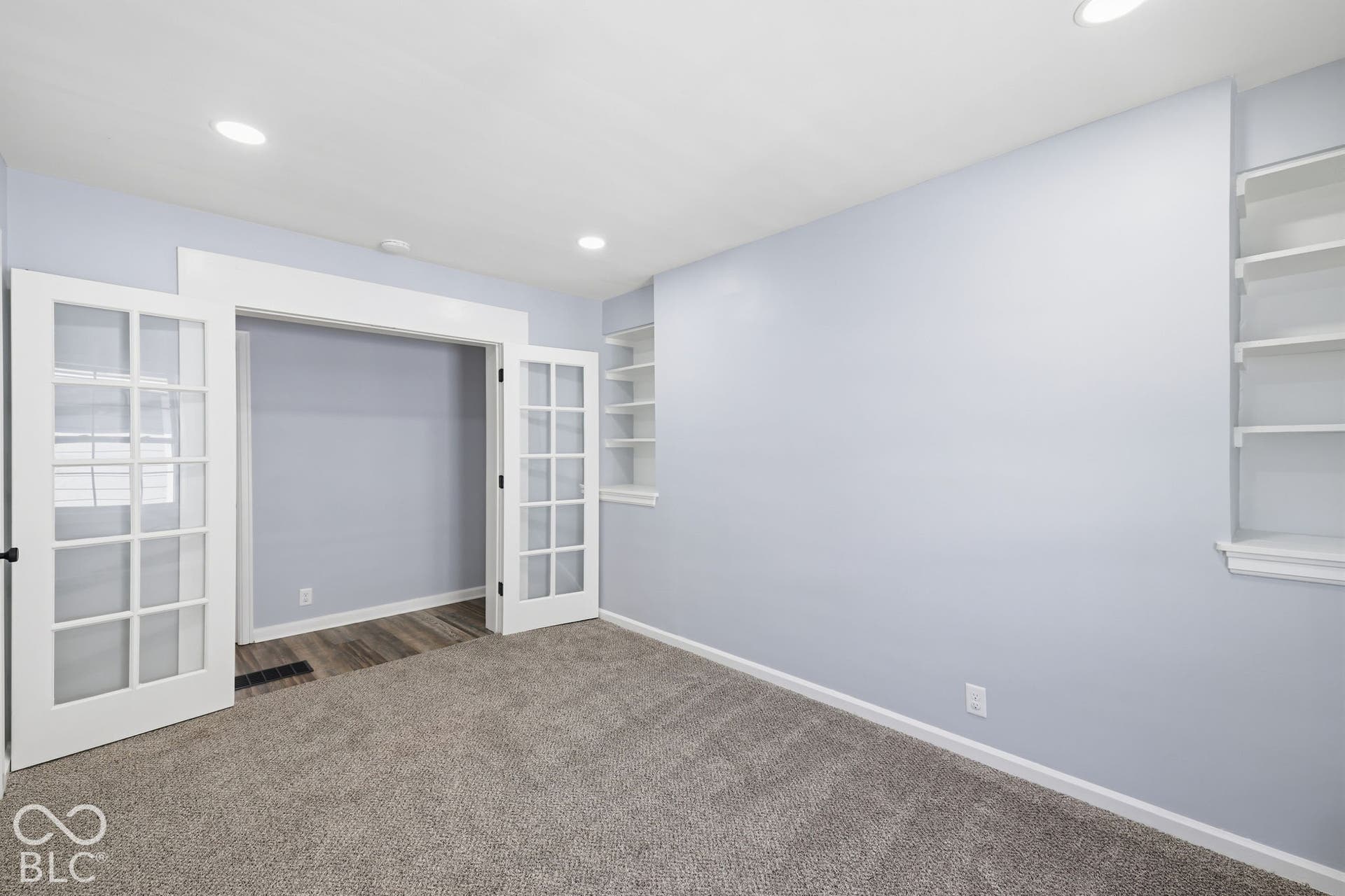 Recessed lighting illuminates the carpeted flooring and built-in shelving