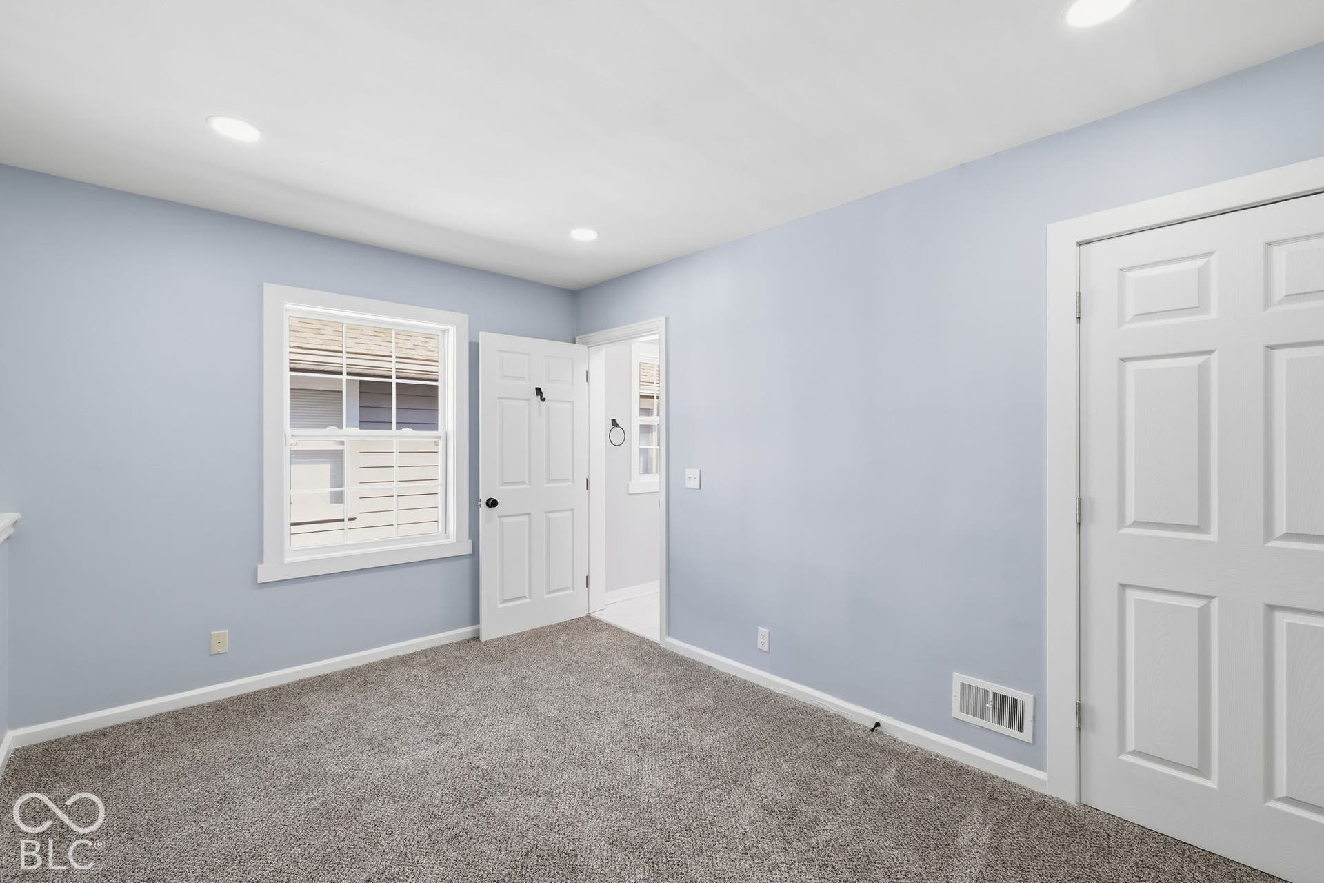 Plush carpet flooring, recessed ceiling lighting, a six-panel door, and a white-trimmed window