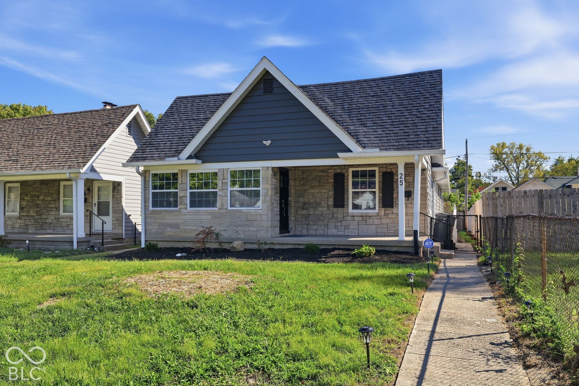 Exterior featuring stone facade, dark siding accents, a covered front porch, and a concrete walkway