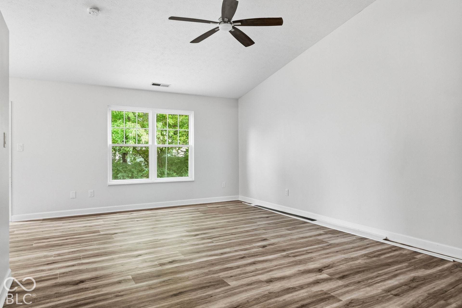 Vaulted ceiling with a ceiling fan, wood-finish flooring, and white walls