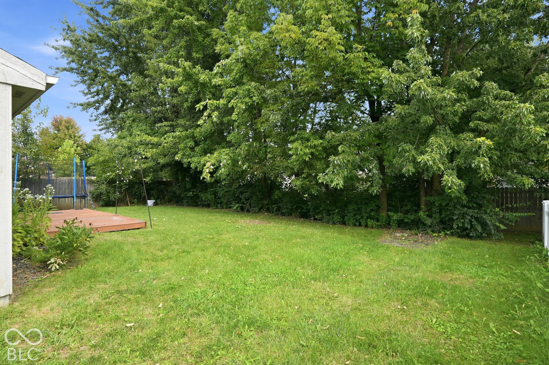 Expansive lawn with mature trees and a wood deck