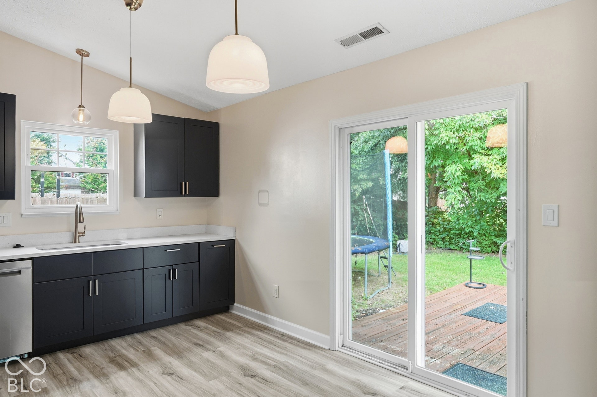 Kitchen featuring dark cabinetry, light countertops, wood-finish flooring, and pendant lighting