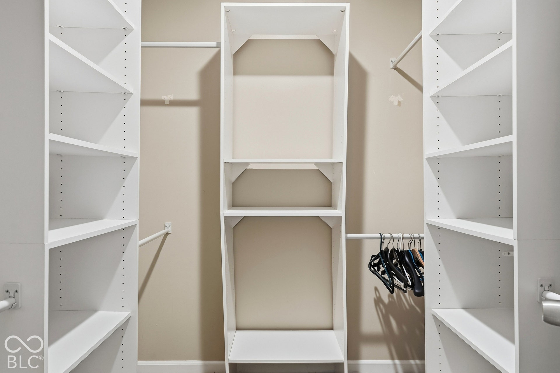 Built-in closet organization system with white shelving, multiple hanging rods, and adjustable shelves