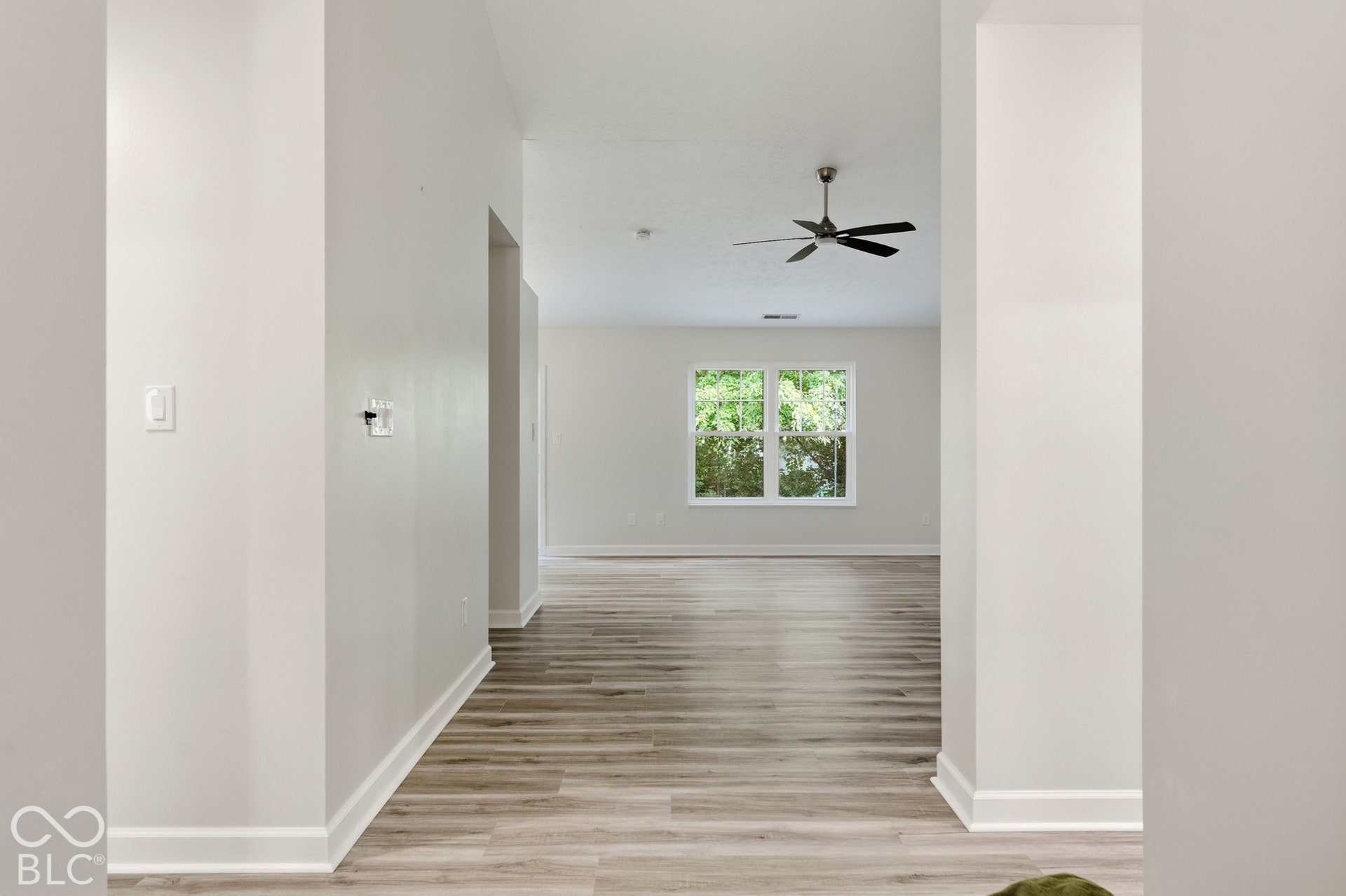 Wood-finish flooring throughout, white walls, and a double window