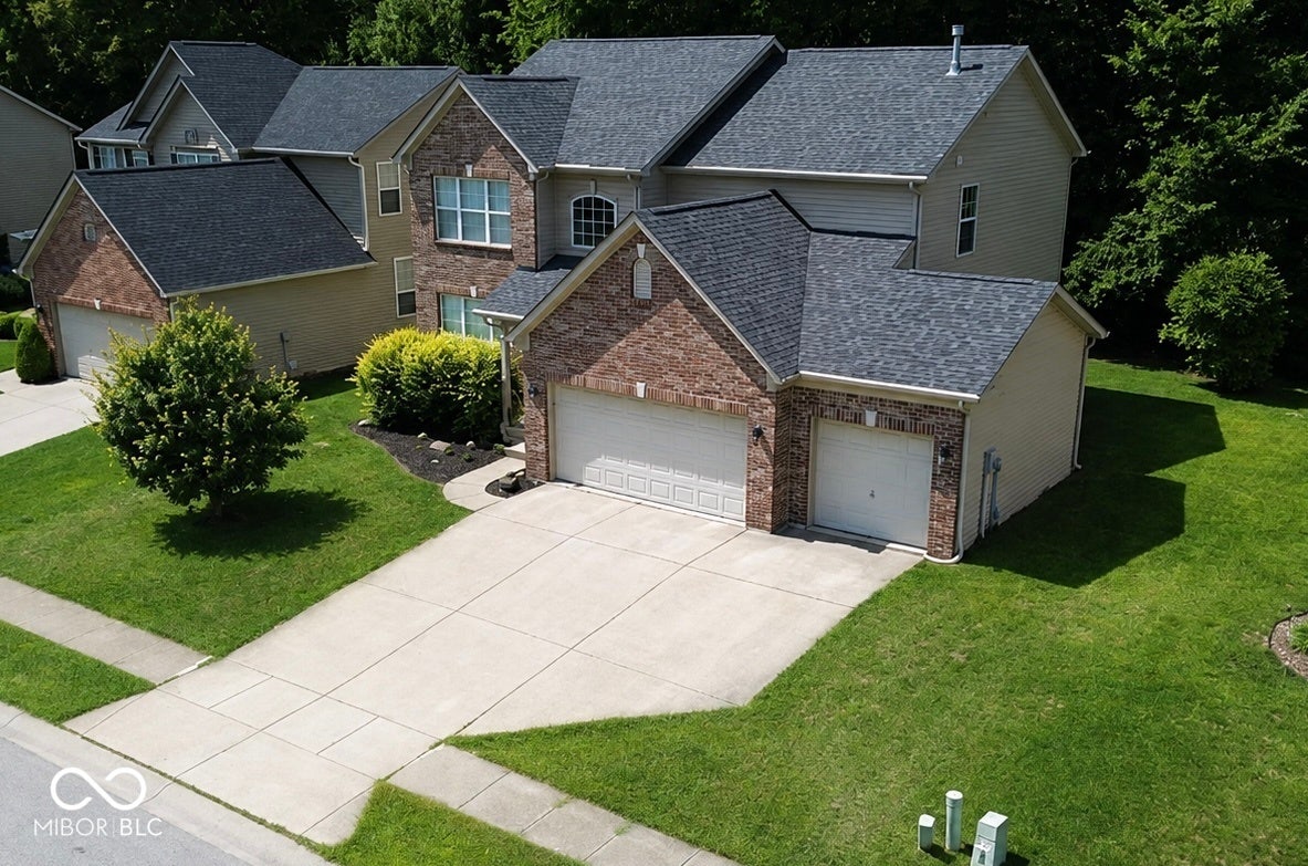 Brick and siding exterior featuring a multi-car garage, concrete driveway, and mature landscaping