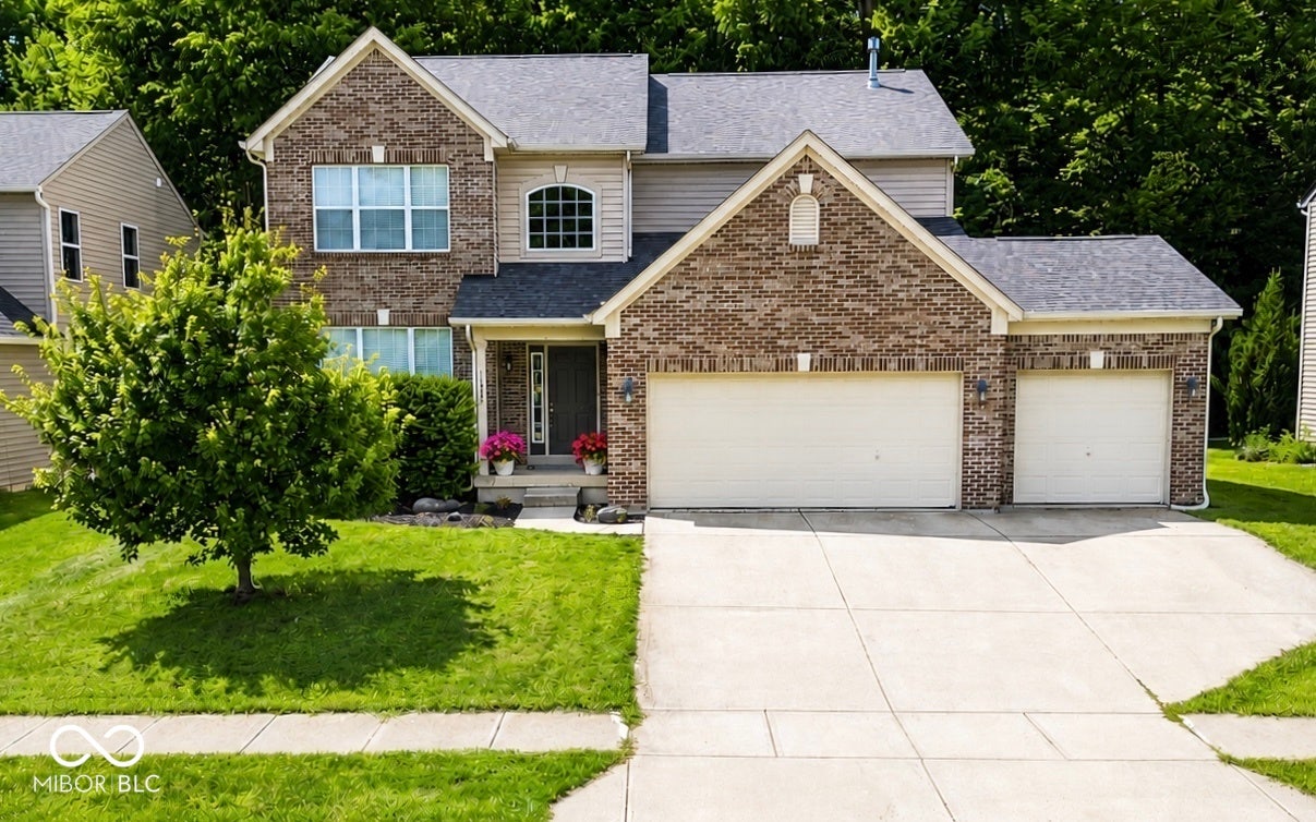 NEW ROOF! Brick facade with light-colored siding, front entry with transom window, double-width driveway, two-car garage, and mature landscaping