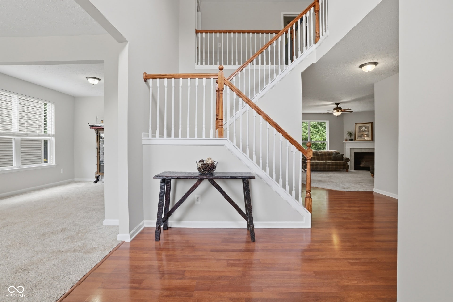Two-story foyer featuring hardwood flooring, a white spindle staircase with wood handrails, and neutral wall paint