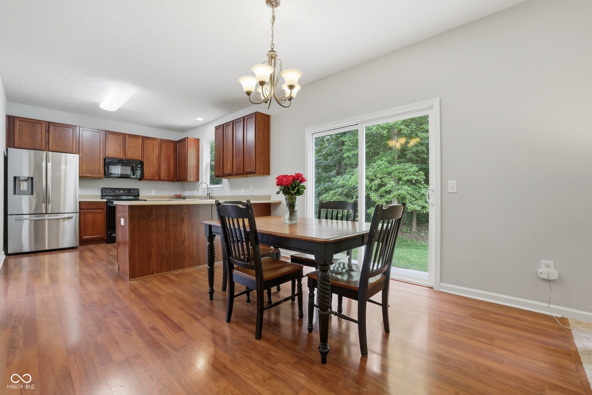 Kitchen and eat in kitchen-dining area featuring wood-finish flooring, warm-toned cabinetry, light countertops, and stainless steel appliances