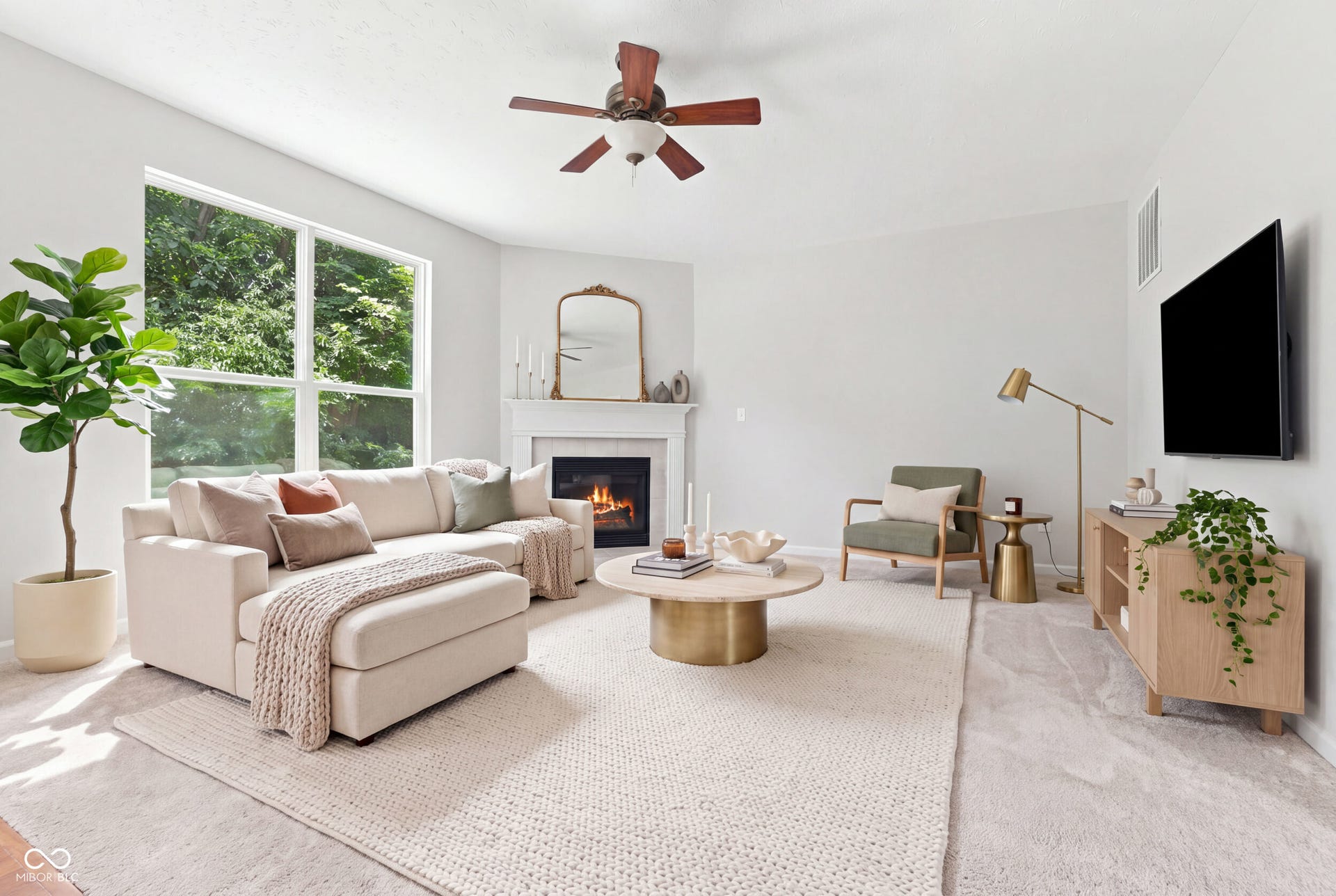 Virtually Altered - Spacious living area featuring a corner fireplace with a white mantel, large windows, and a ceiling fan