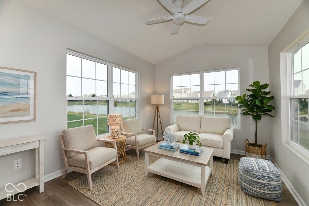 Virtually Altered - Vaulted ceiling with a ceiling fan, large windows, wood-finish flooring, and light-toned walls