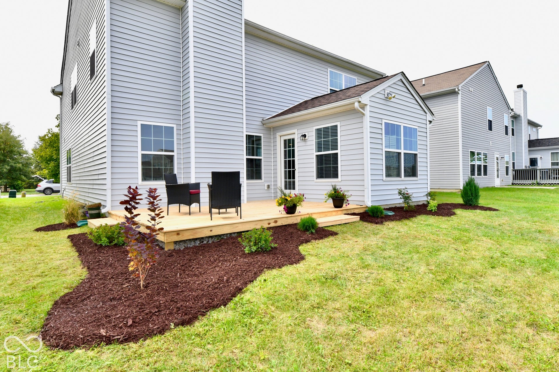 Rear exterior with light gray siding, wood-finish deck, and a sunroom addition