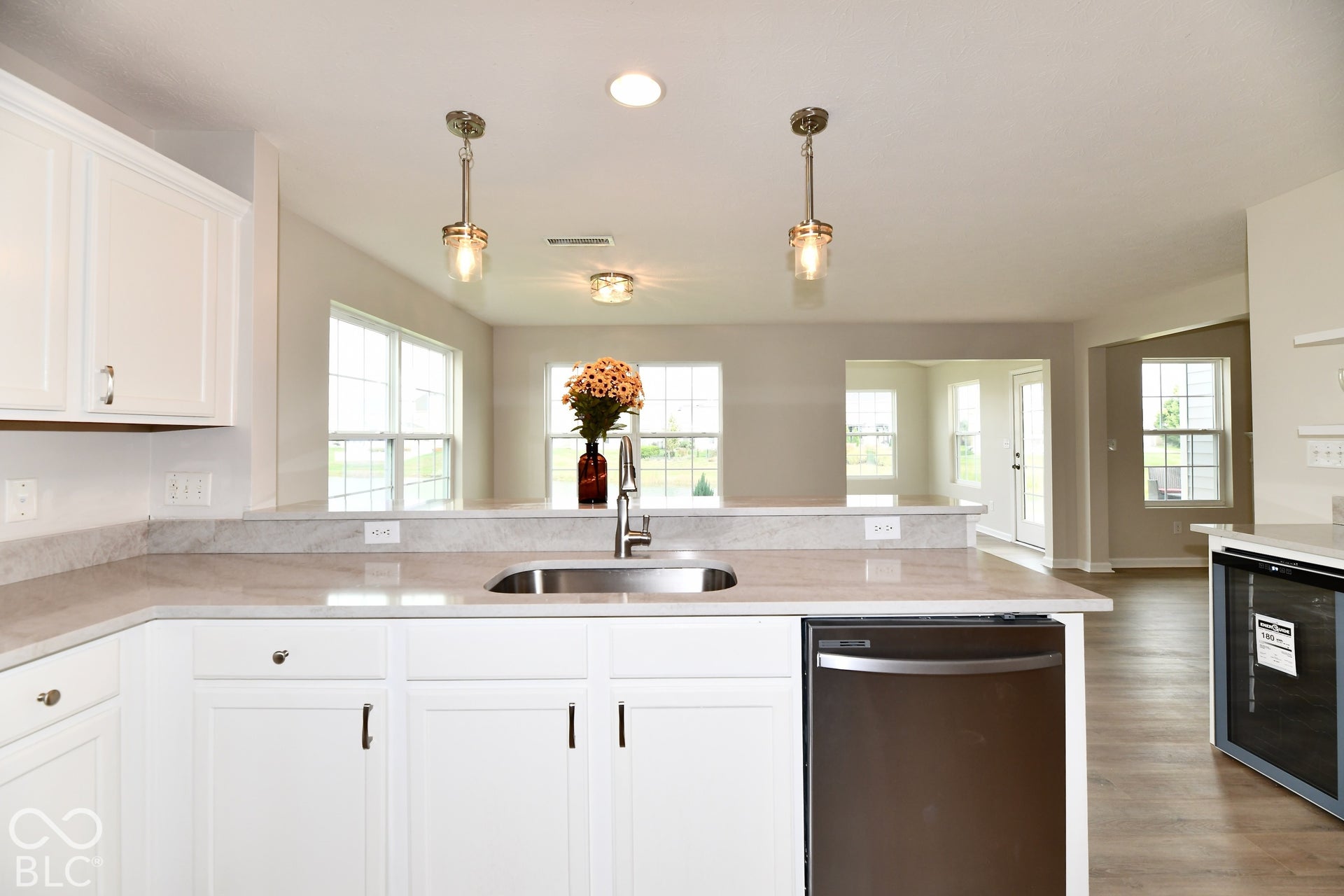 White cabinetry paired with a stainless steel sink, a dark stainless steel dishwasher, and light-toned countertops