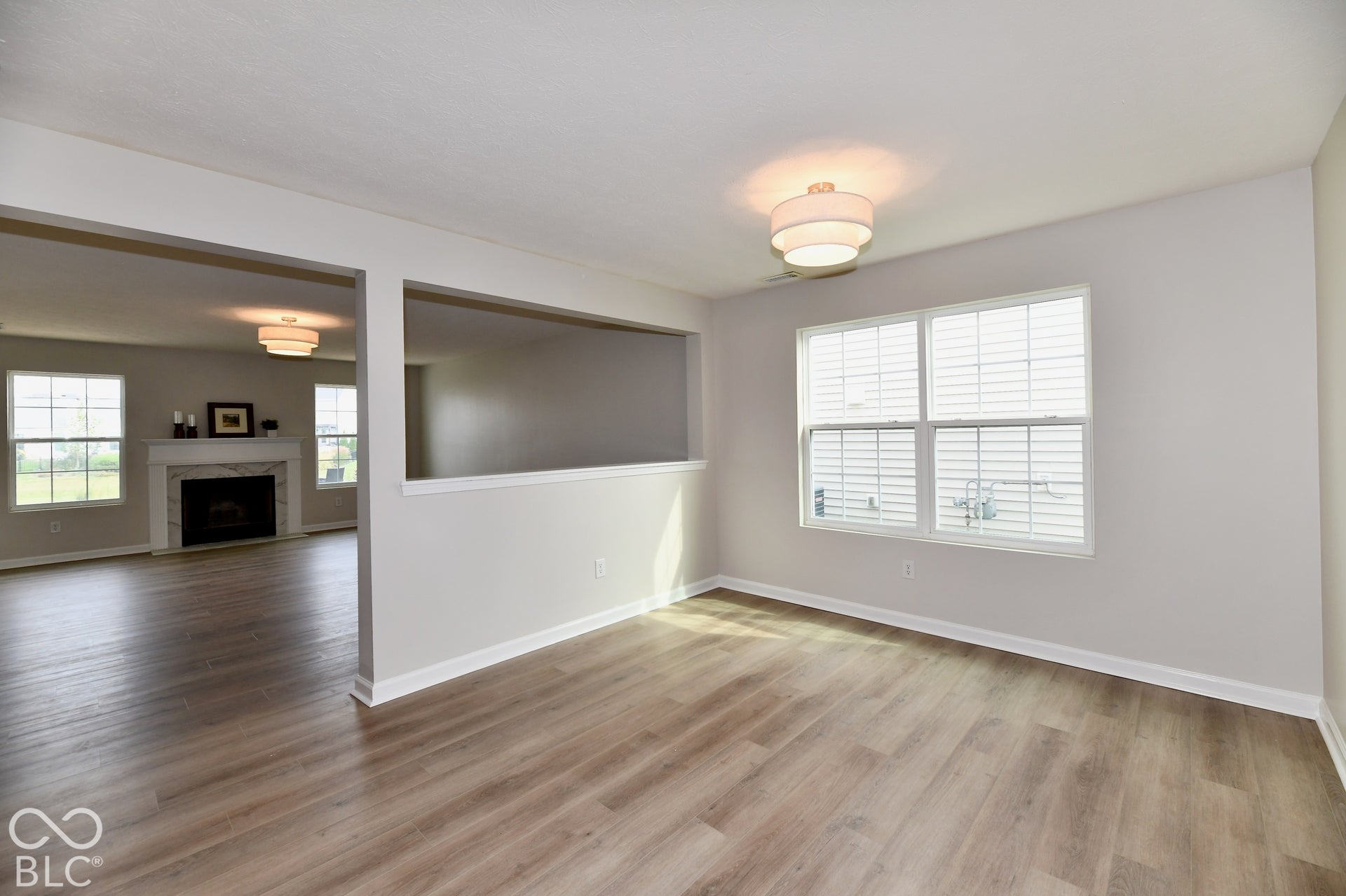 Wood-finish flooring throughout, modern lighting fixture, and white window blinds