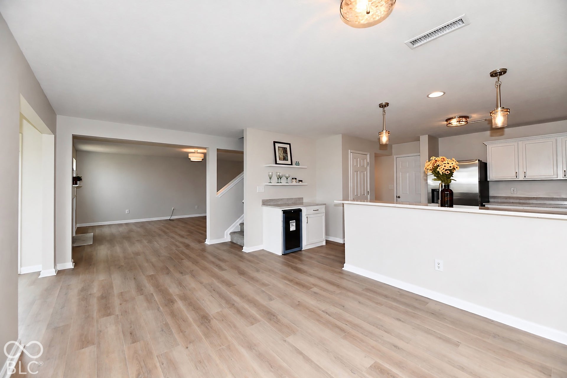 Open-concept living area with wood-finish flooring, recessed lighting, and kitchen peninsula with pendant lighting