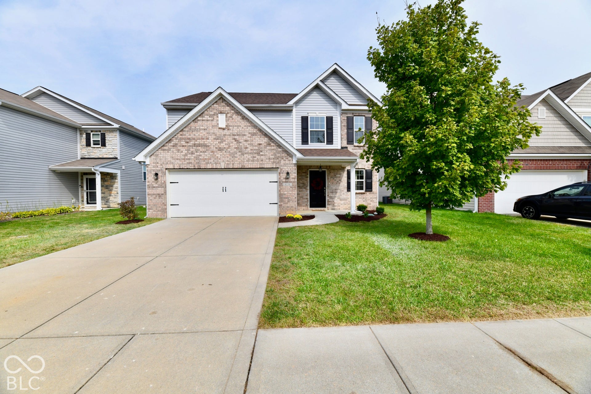Two-story residence featuring a brick and siding facade, a two-car garage, and a concrete driveway