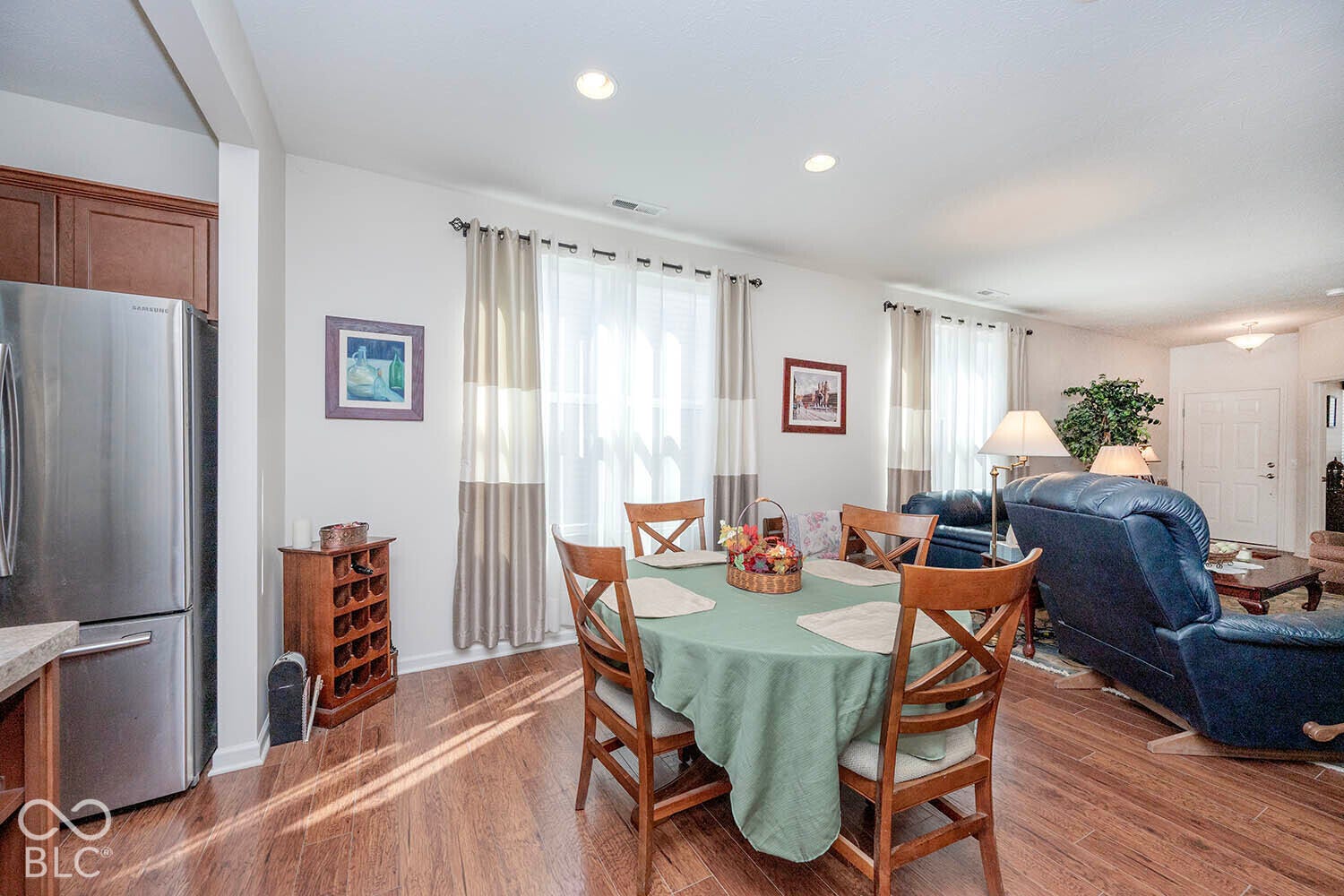 Wood-finish flooring throughout, recessed lighting, and a stainless steel refrigerator