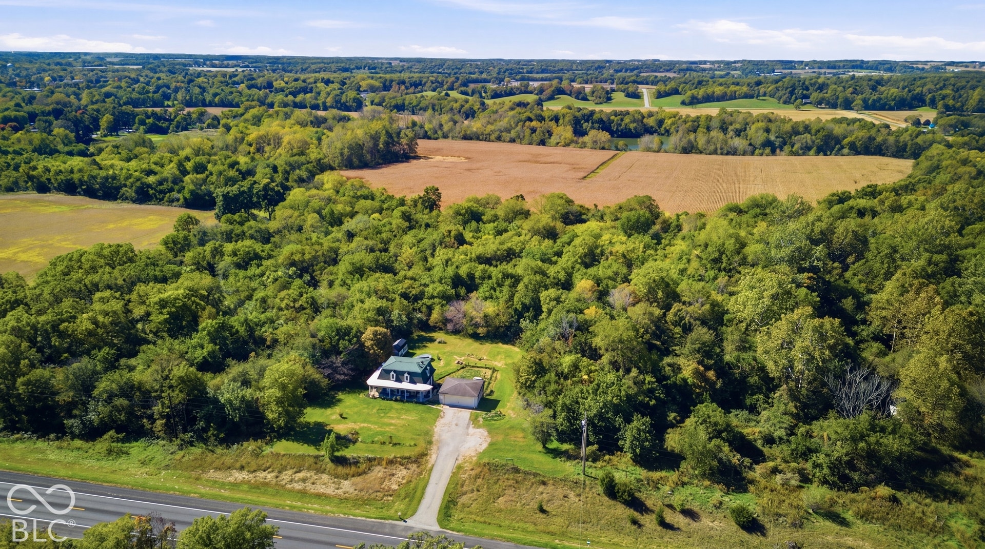 Expansive rural setting with a single-family residence, mature trees, and agricultural land