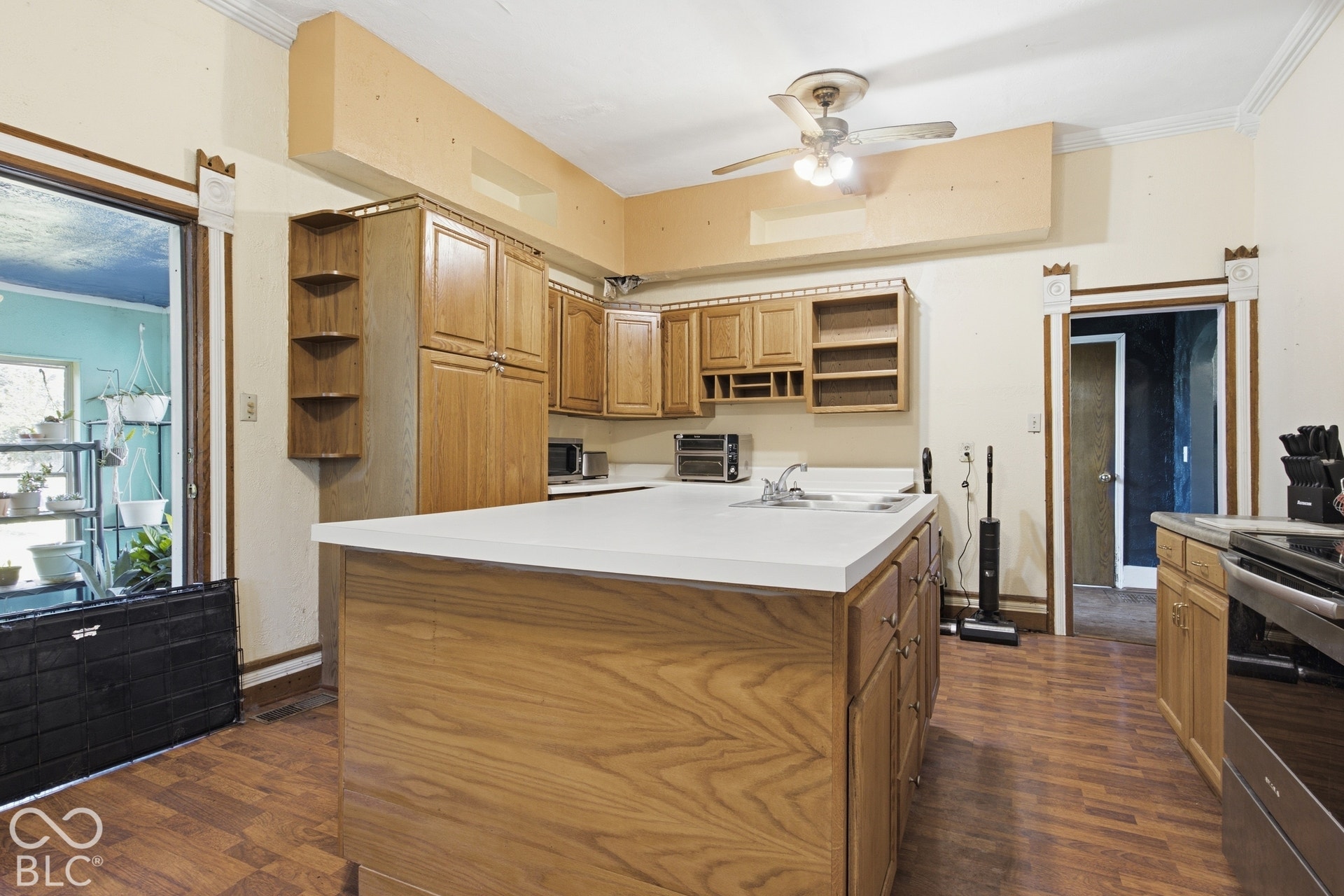 Kitchen featuring wood-finish flooring, wood cabinetry, light-toned countertops, and a ceiling fan with integrated lighting