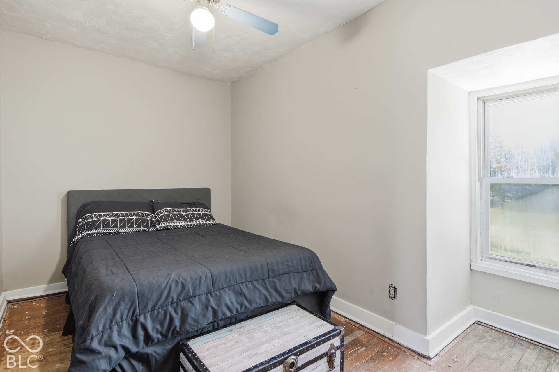 Bedroom featuring a wood-finish floor, ceiling fan, and large window with natural light