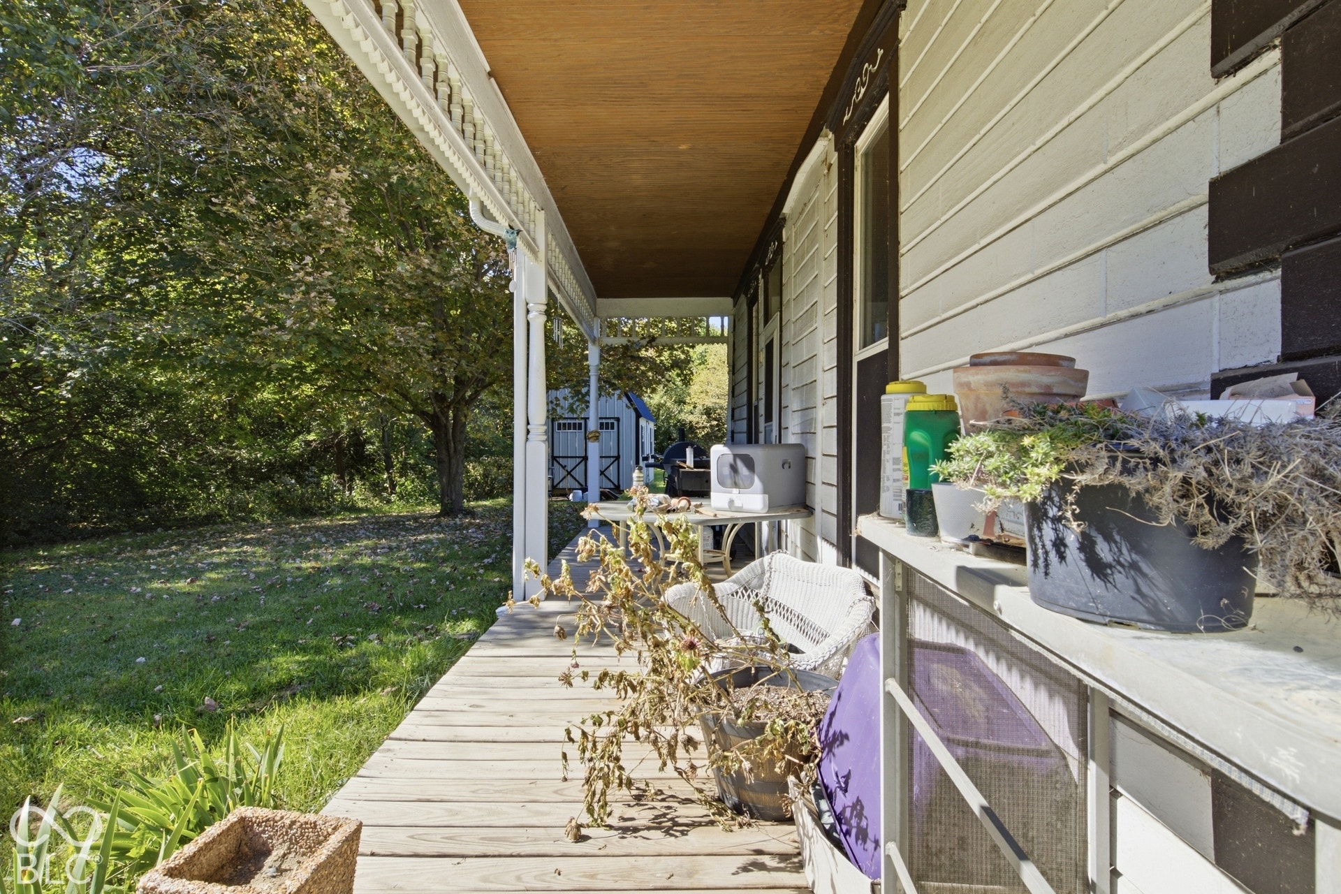 Wood-finish porch decking with a decorative white railing and columns