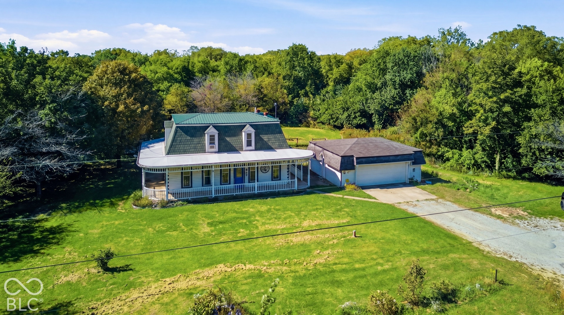 Virtually Altered - Two-story residence with a green gambrel roof, dormer windows, and a wraparound porch