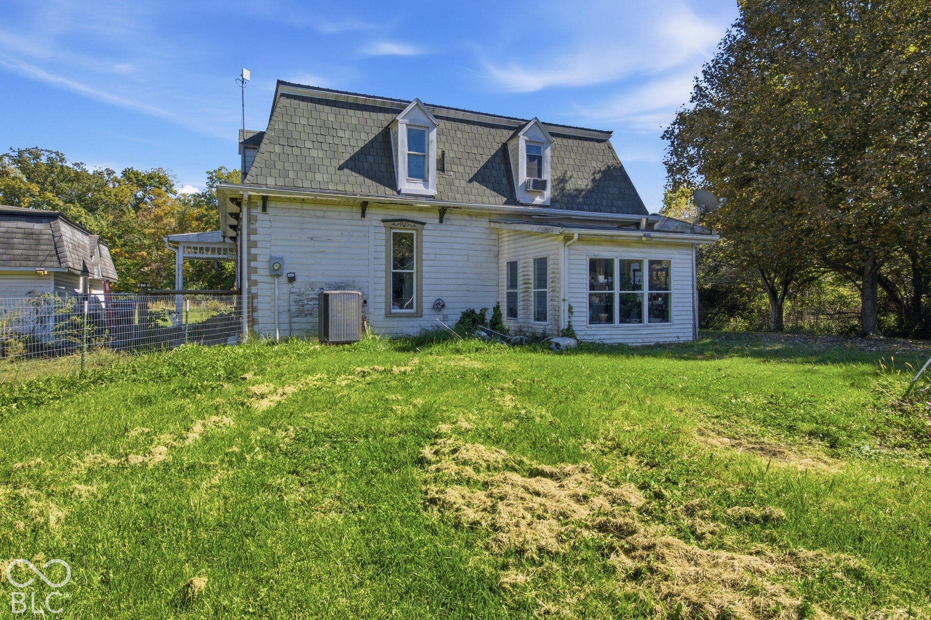 White siding exterior with a dark shingle roof and multiple dormer windows