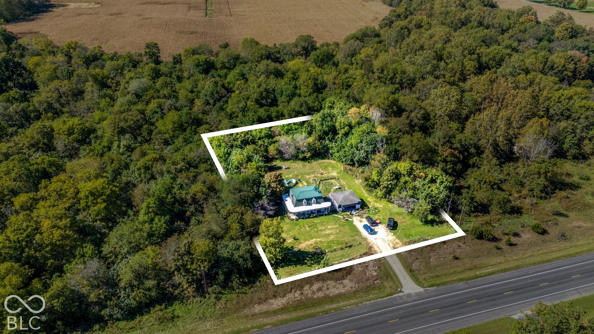 Property featuring two distinct structures, surrounded by mature trees and a substantial green space