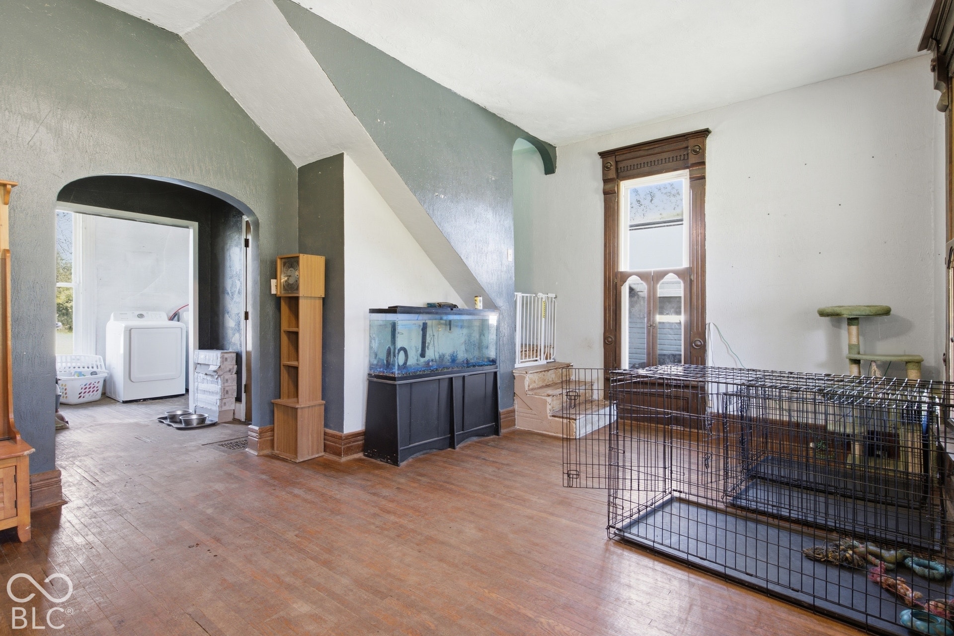 Wood-finish flooring throughout, featuring a rounded archway and a decorative window frame