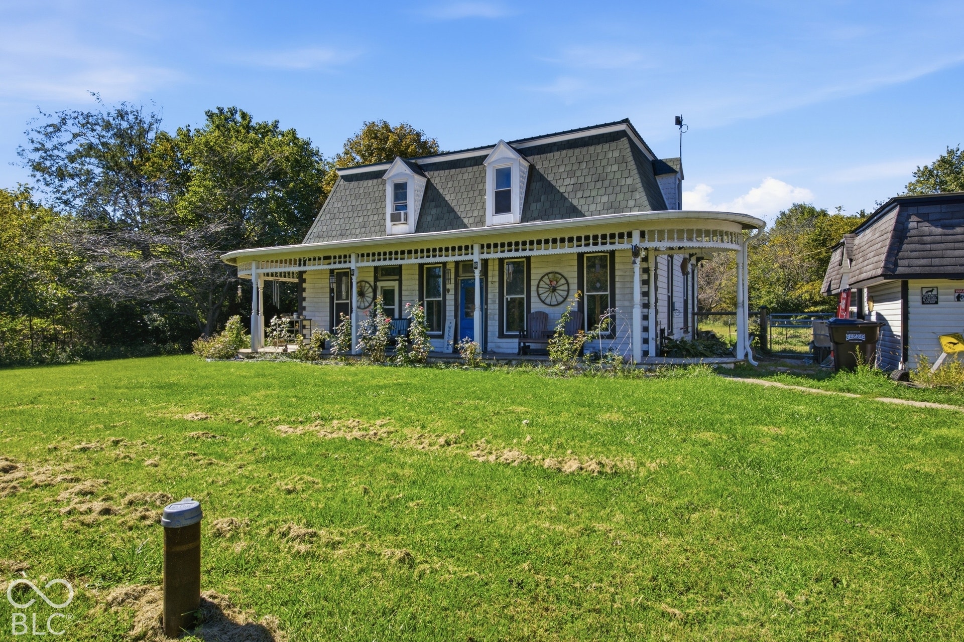 Victorian-style architecture featuring a wraparound porch, detailed spindle work, a gambrel roof, and multiple dormer windows