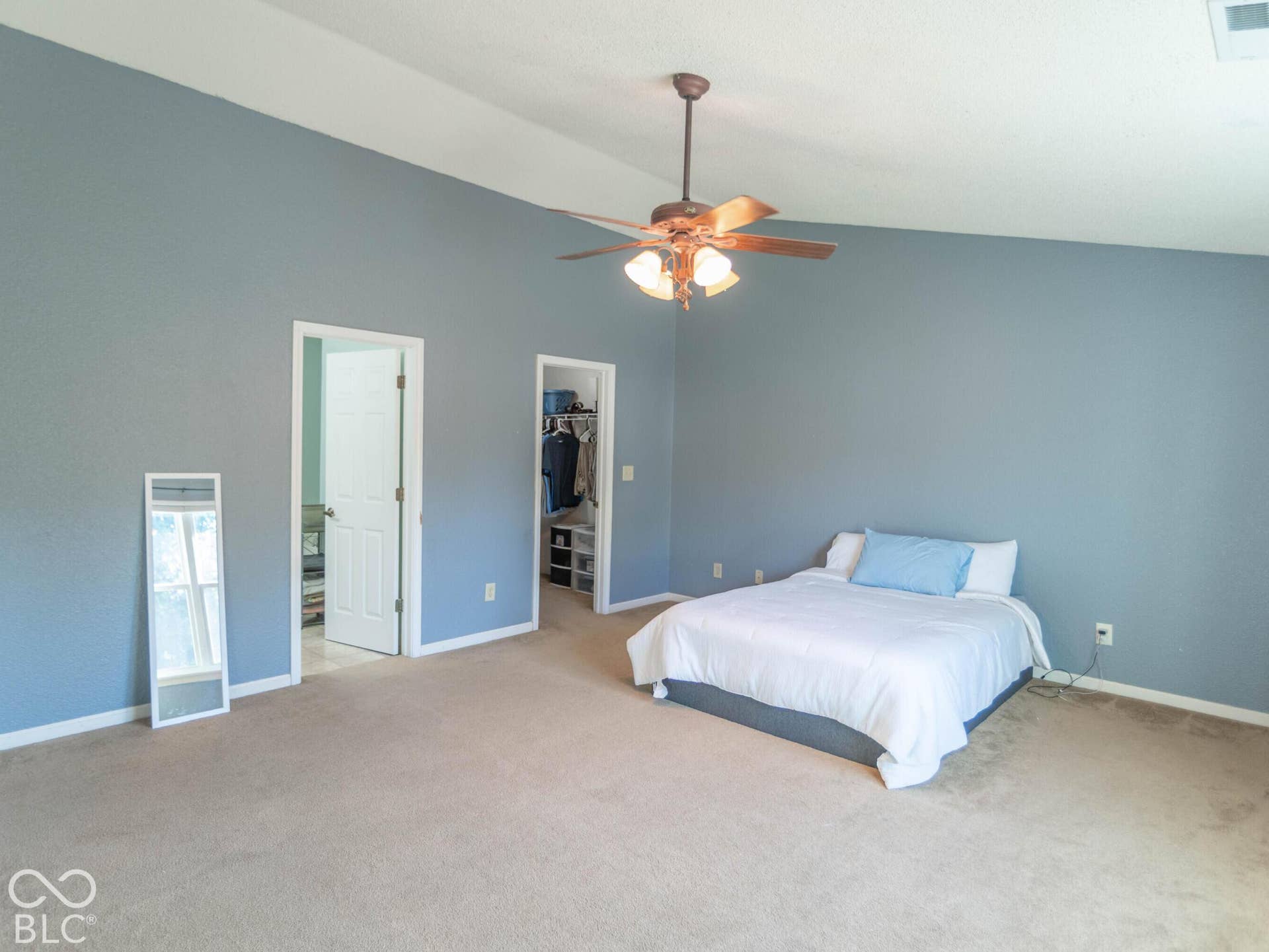 Primary bedroom with ensuite and large walk-in closet. Vaulted ceiling with a ceiling fan light fixture
