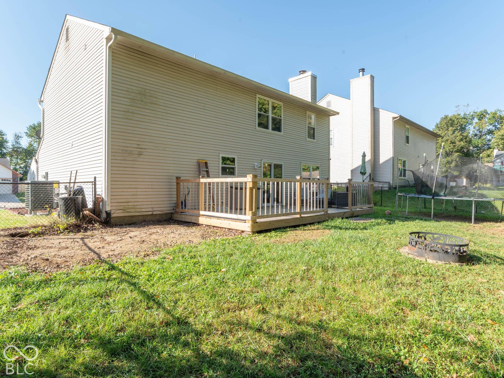 Expansive fenced backyard featuring a spacious wooden deck with railings