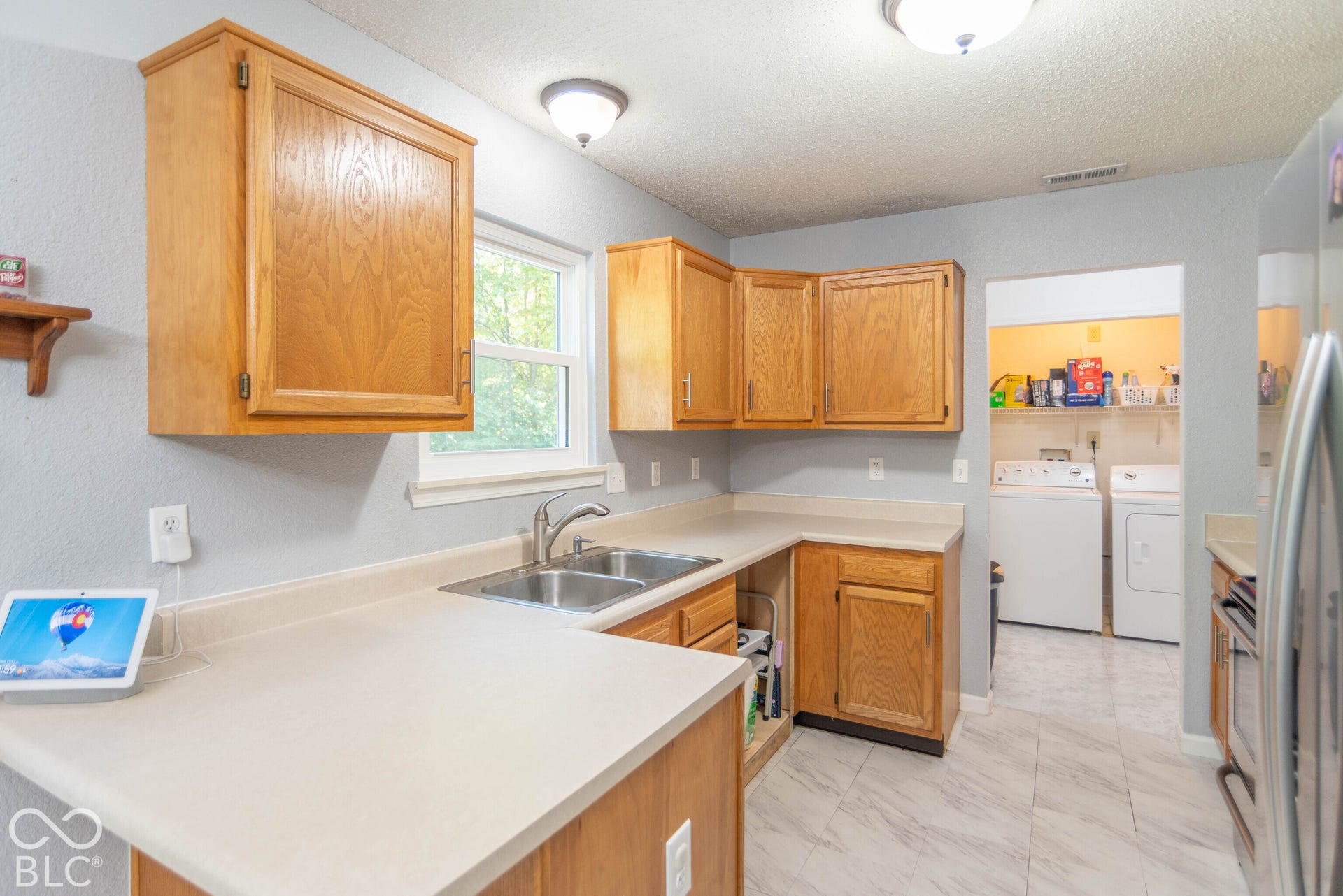 Kitchen with light wood cabinetry, dual basin stainless steel sink, and light-toned countertops