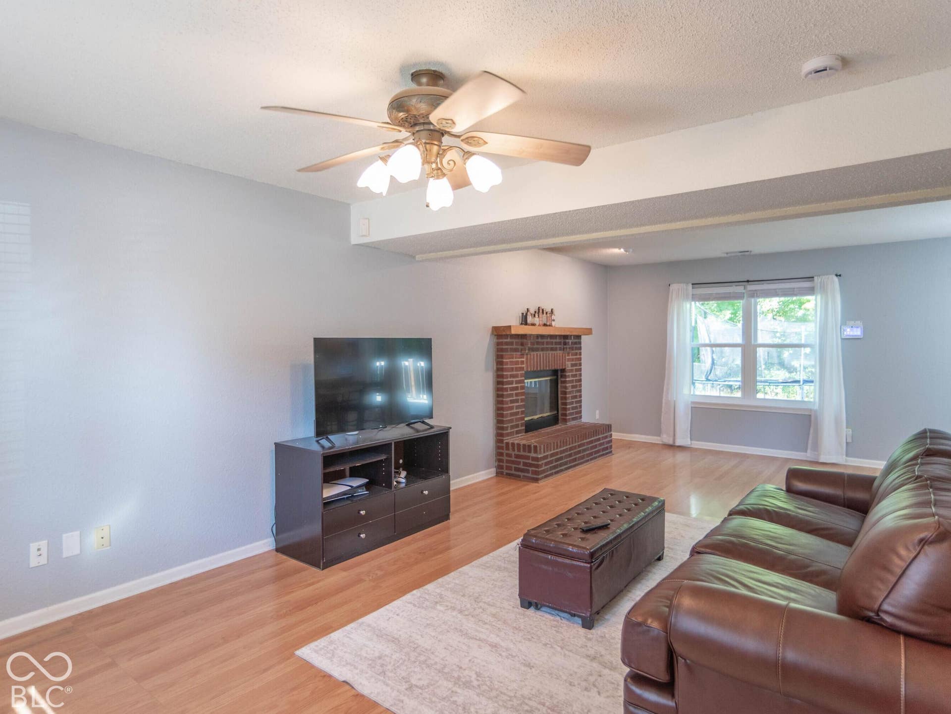 Spacious living room showcasing hardwood flooring, and a ceiling fan with integrated light fixture