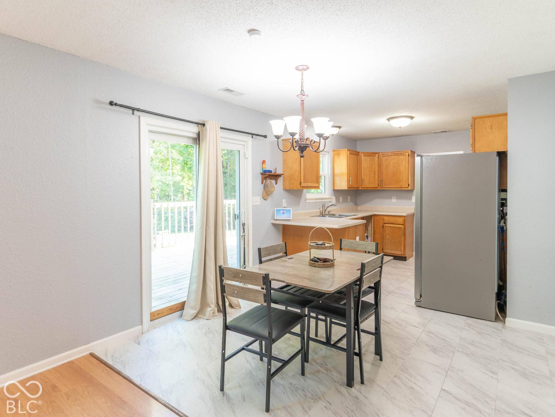 Kitchen featuring wood-finish cabinetry, stainless steel refrigerator, patio door opens to wood deck