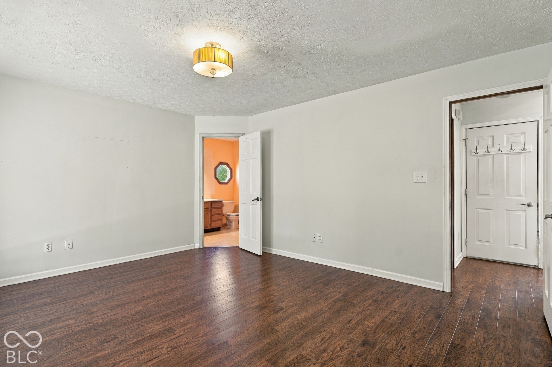 Wood-finish flooring throughout, light neutral wall paint, and a classic ceiling-mounted light fixture