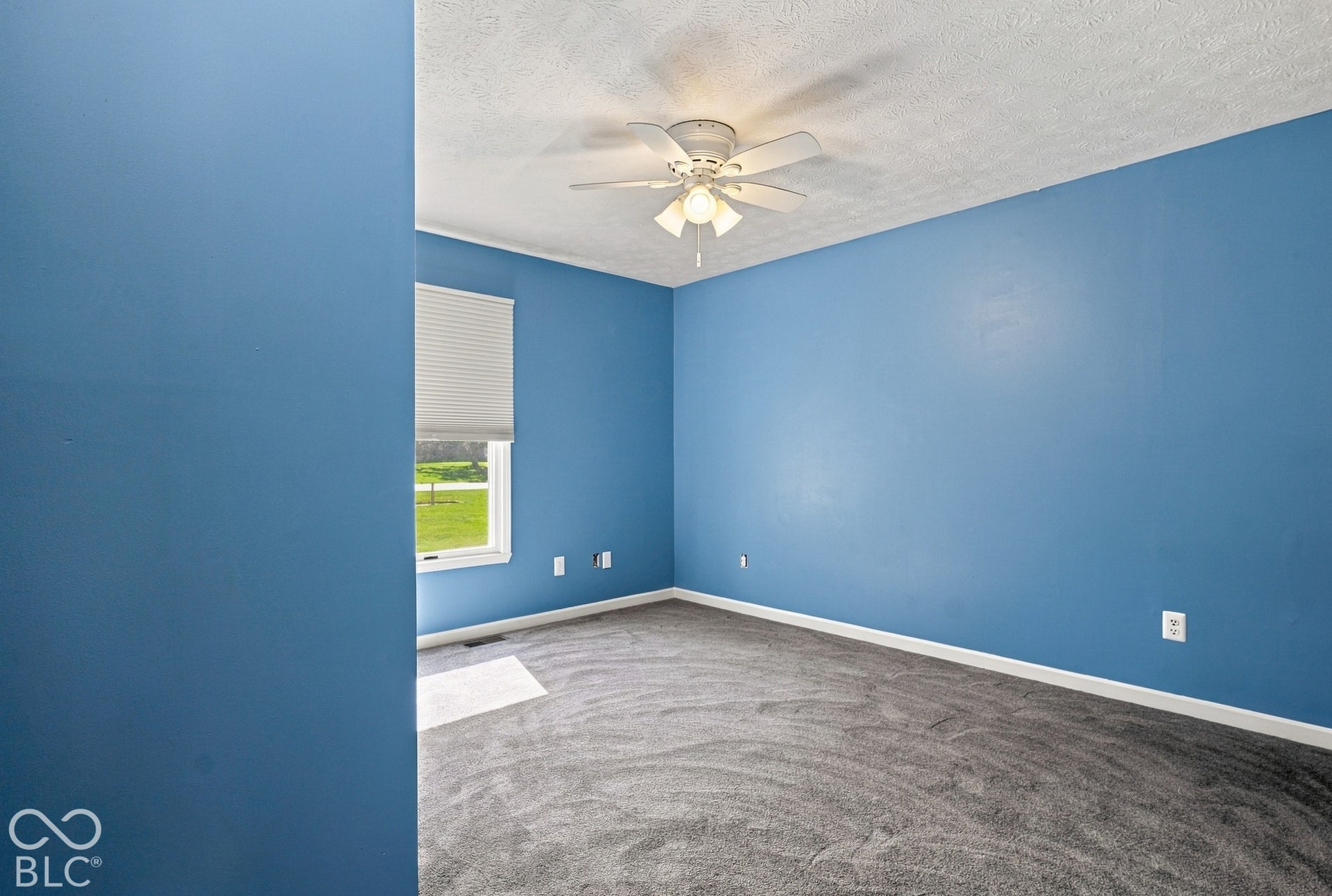 Recessed window with horizontal blinds, overhead ceiling fan with lighting, wall-to-wall carpeting, and white baseboards