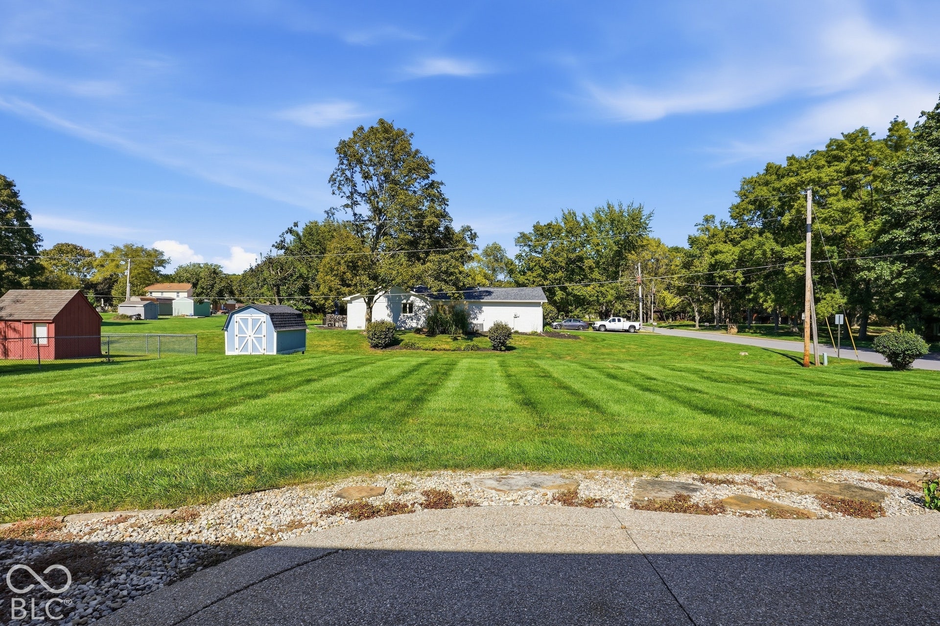 Expansive green lawn with striped mowing patterns, bordered by established trees