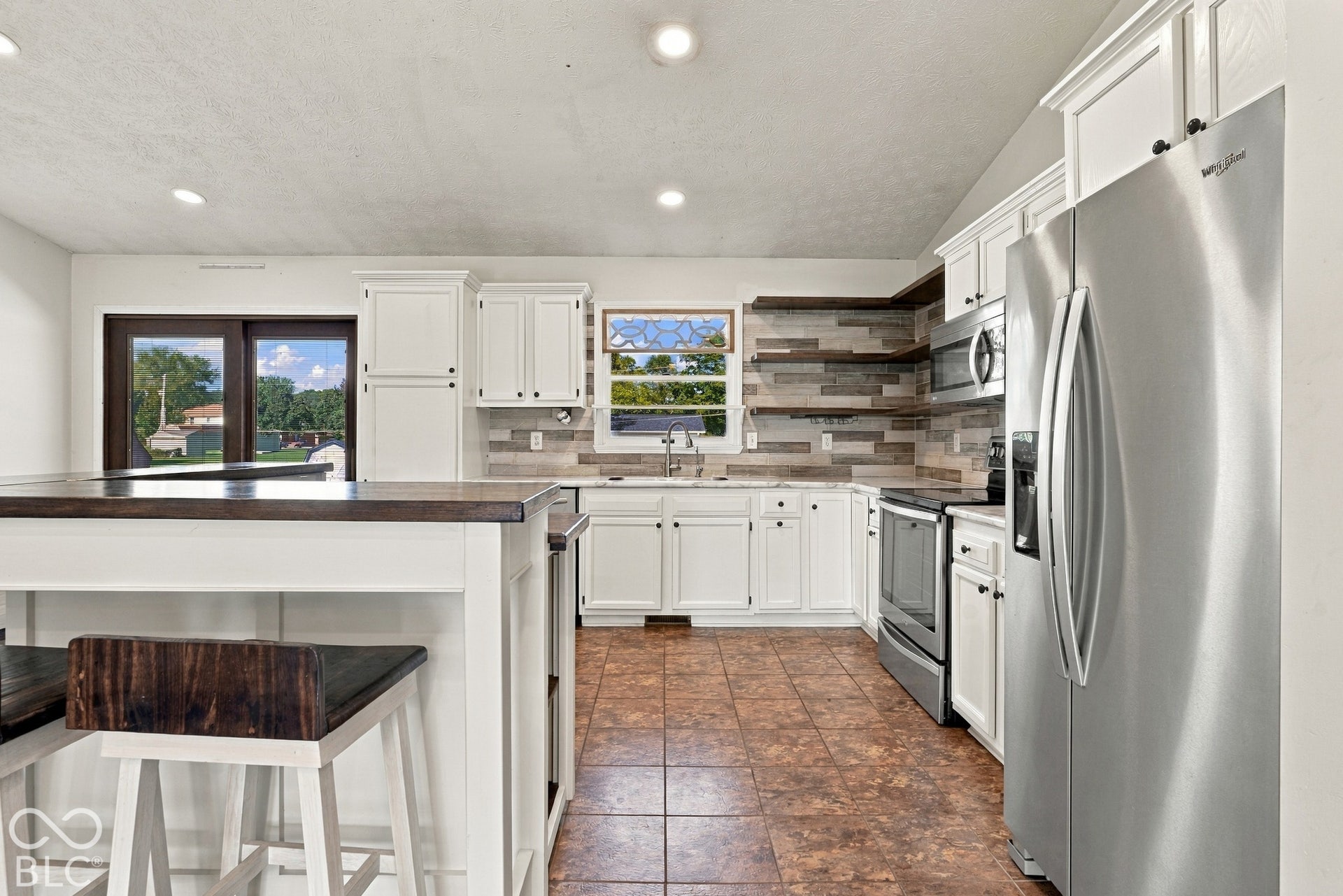White cabinetry with dark hardware, stainless steel appliances, and a mosaic tile backsplash