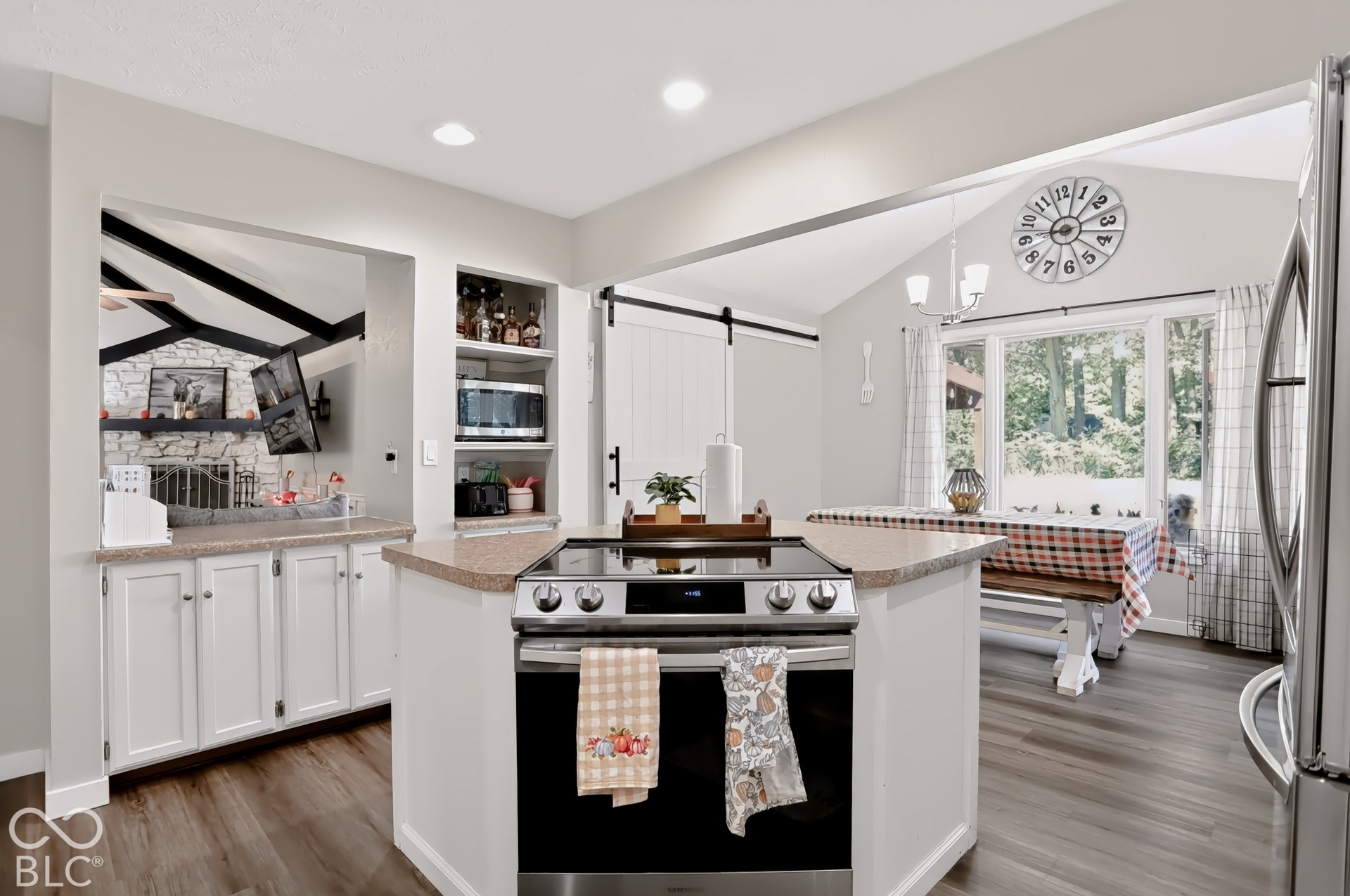 Kitchen featuring a center island with built-in range, wood-finish flooring, white cabinetry, and built-in shelving