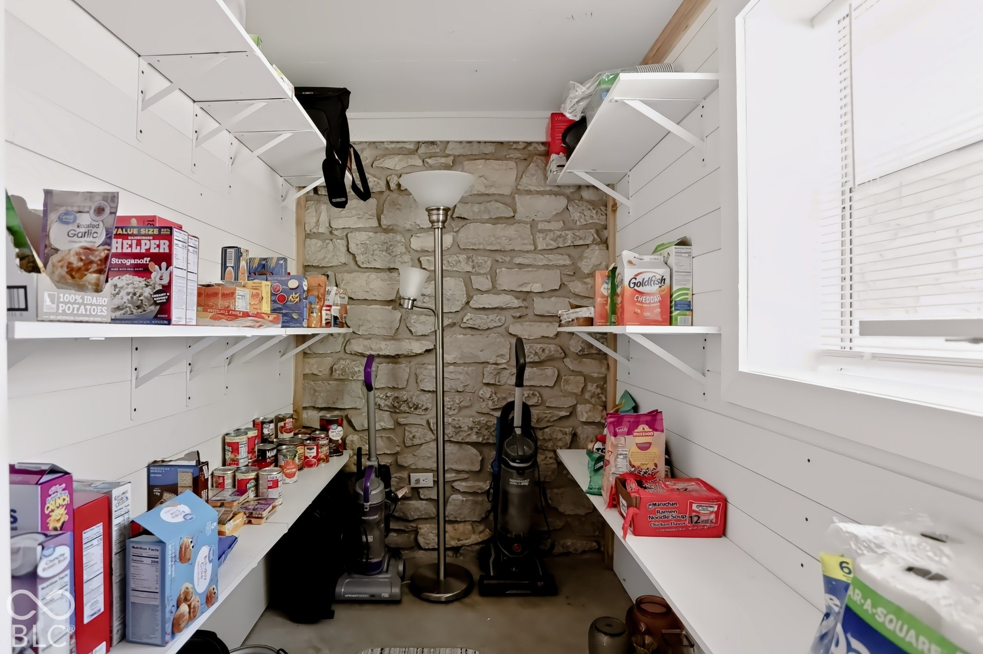 Built-in shelving, stone accent wall, window with blinds, white shiplap walls, and recessed lighting