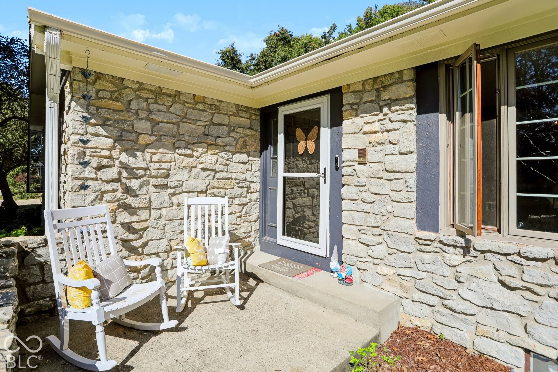 Stone facade with a concrete front porch, featuring a storm door entry and a casement window