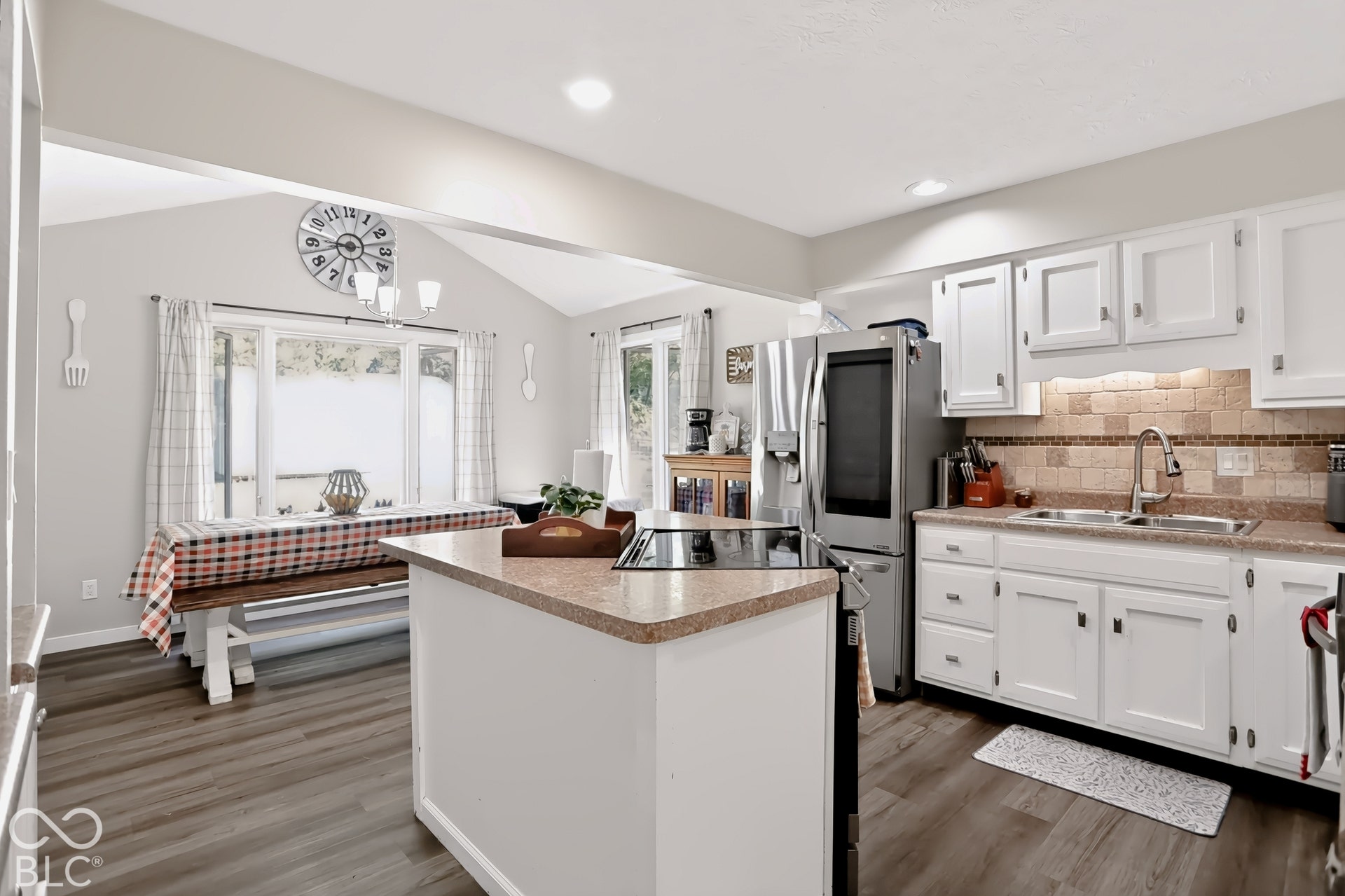 Kitchen featuring an island cooktop, white cabinetry, stainless steel refrigerator, and a tiled backsplash