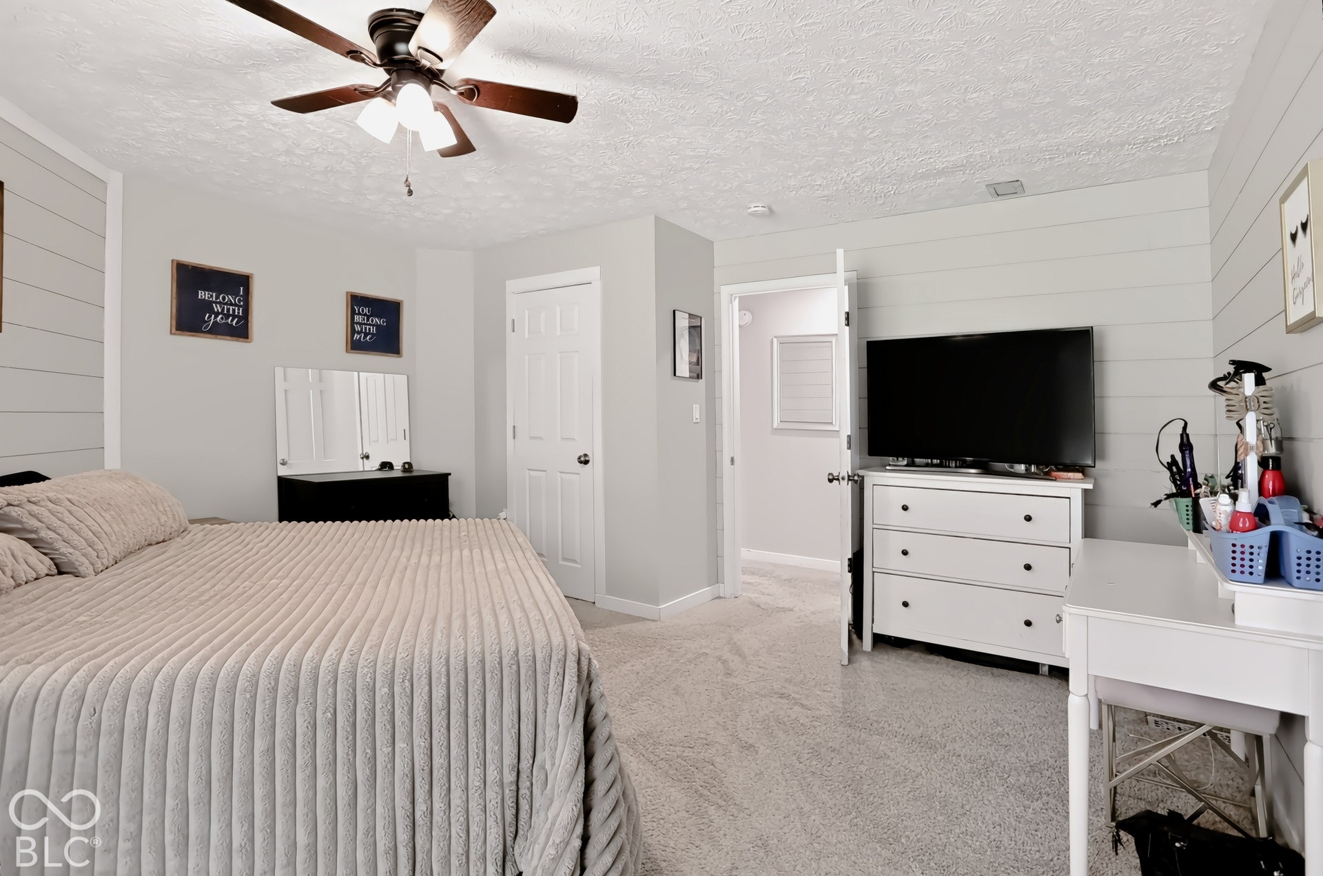 Carpet flooring, ceiling fan with integrated lighting, paneled accent wall, and a white interior door