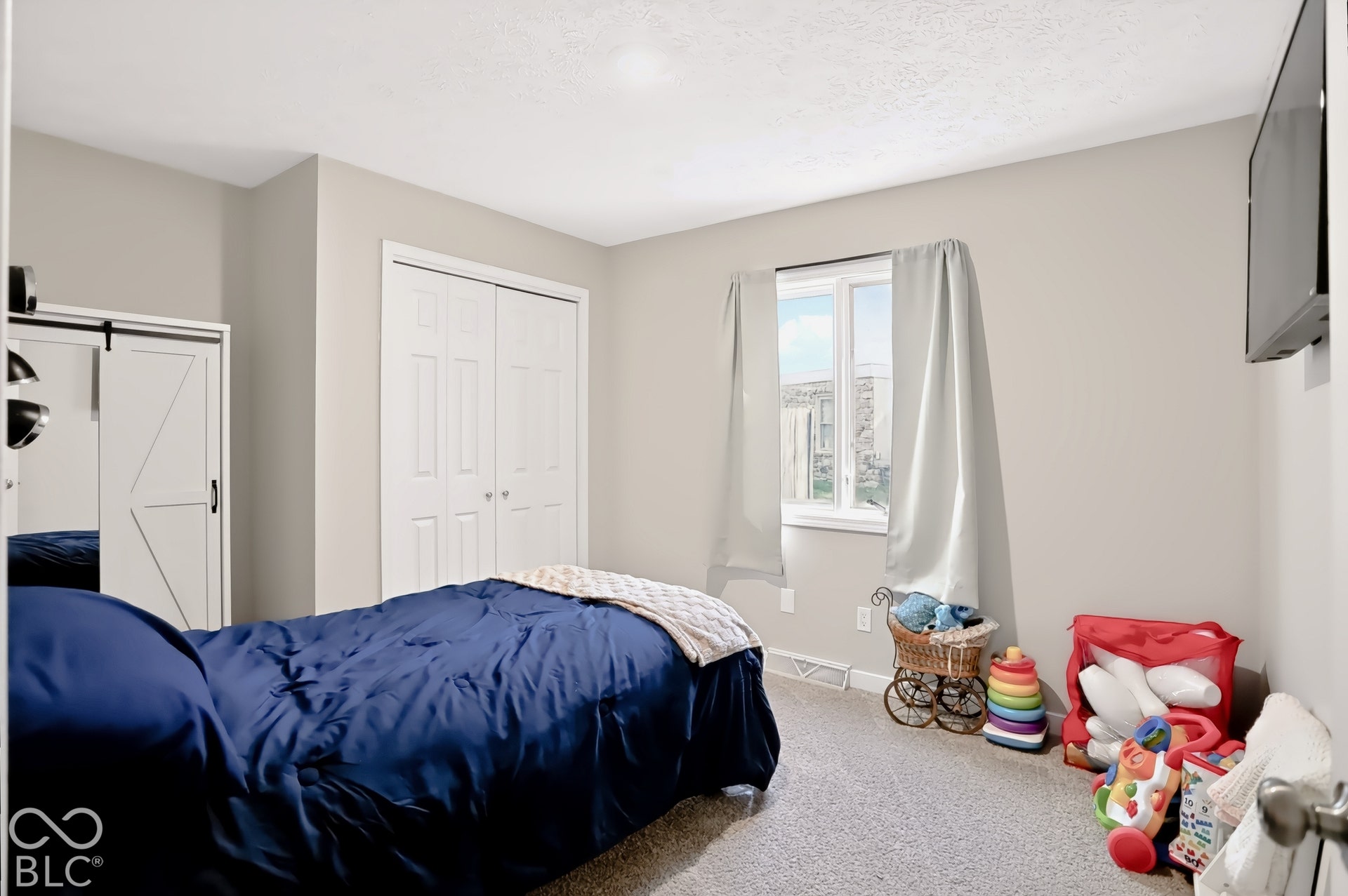 White bi-fold closet doors, a single window, and neutral wall paint
